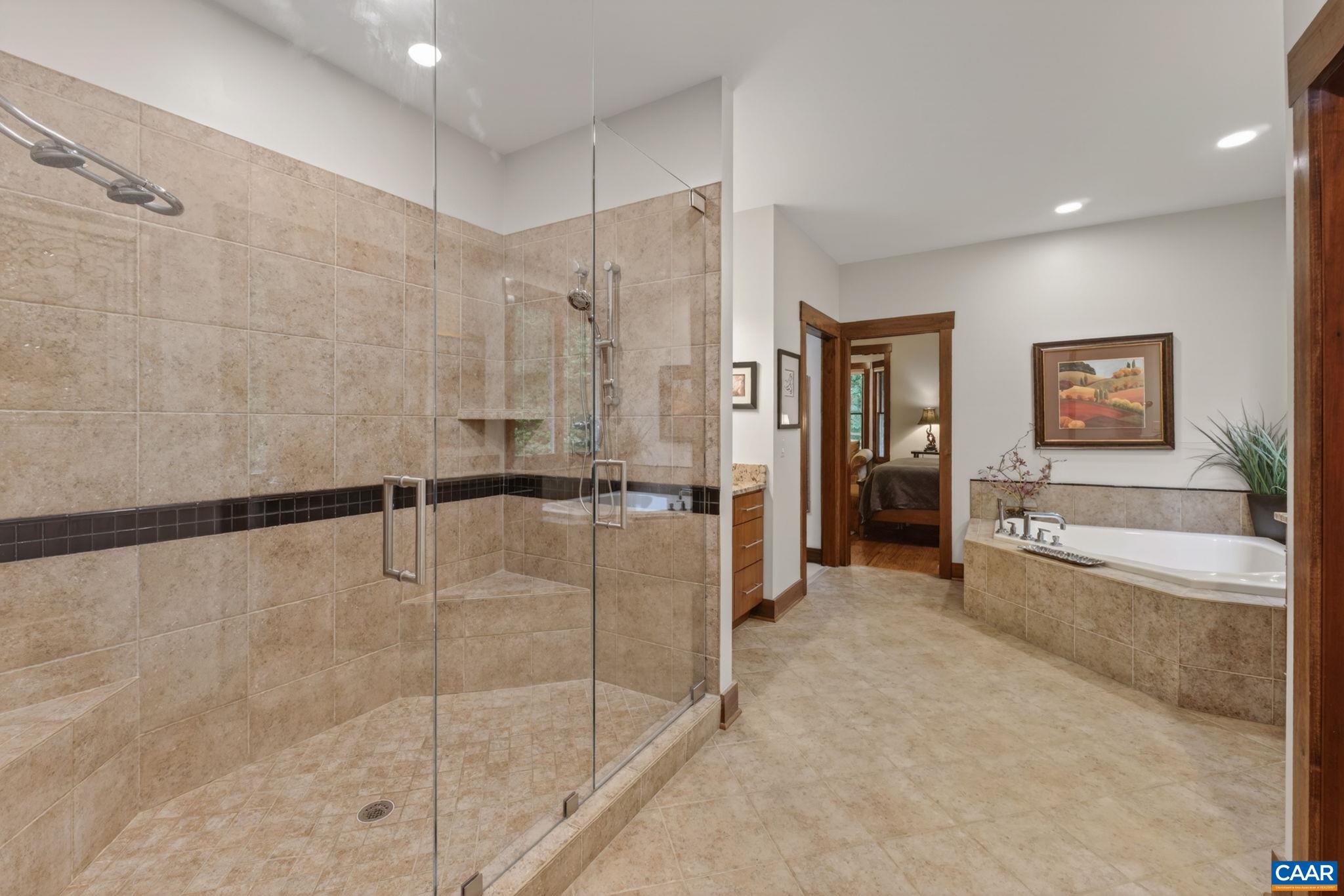 Fully tiled primary bathroom with soaking tub and multi-headed shower. Fully tiled primary bathroom with soaking tub and multi-headed shower.