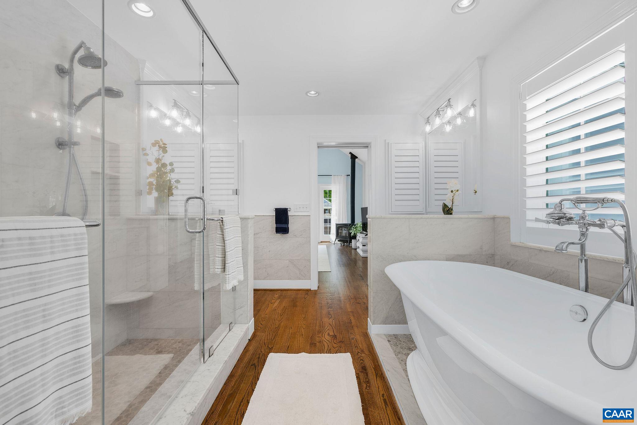 Karen Turner designed primary bath with soaking tub, walk in shower, separate vanities, and high end carrera marble finishes.