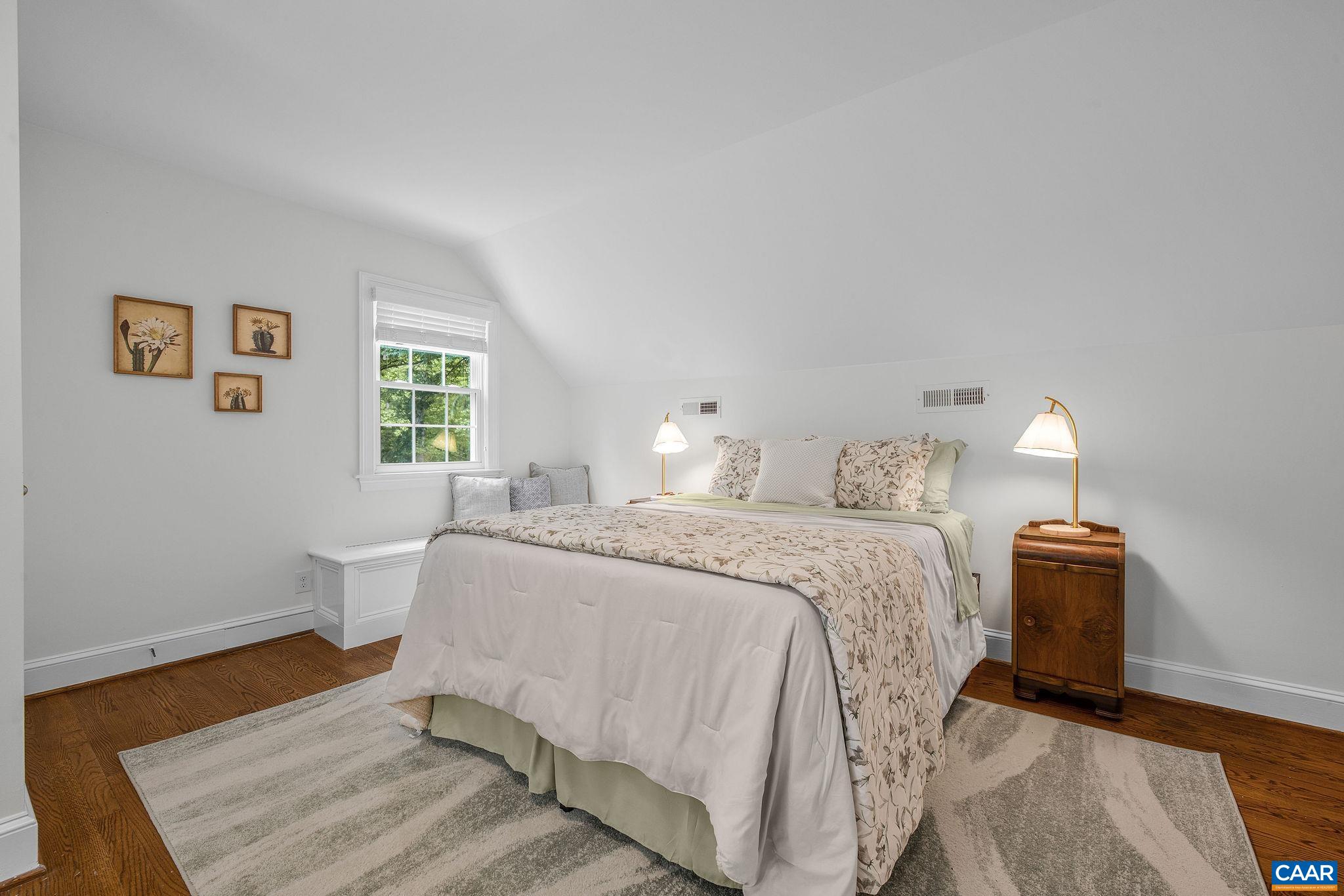 Large bedroom on the upper level features hardwood floors and a sunny sitting area.