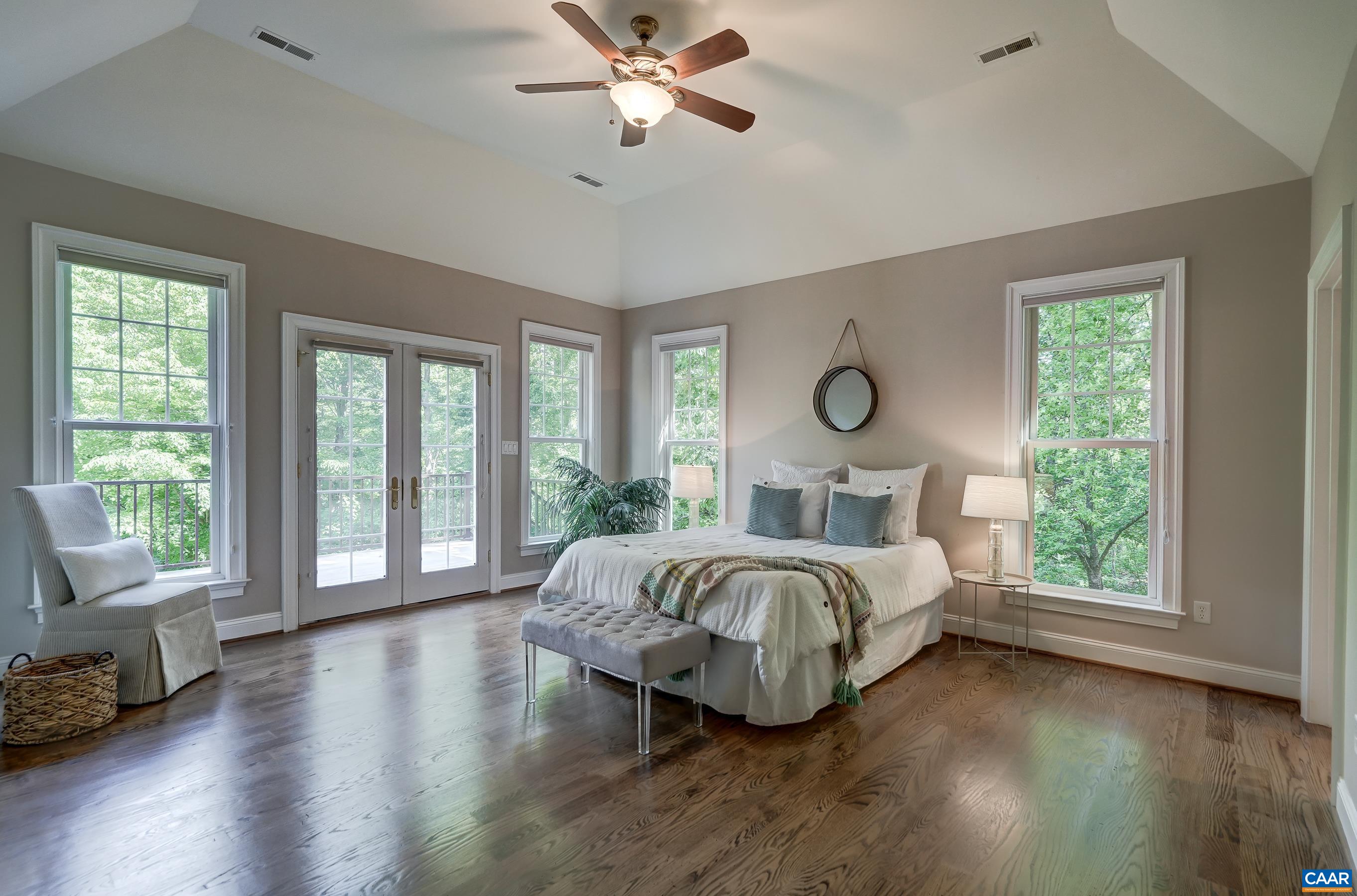 Primary suite with hardwood floors, ceiling fan and high ceilings