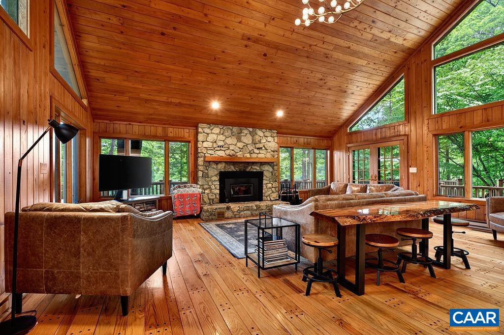 A dramatic great room with cathedral ceilings, a stunning real stone wood-burning fireplace, and an abundance of windows filling the space with natural light.