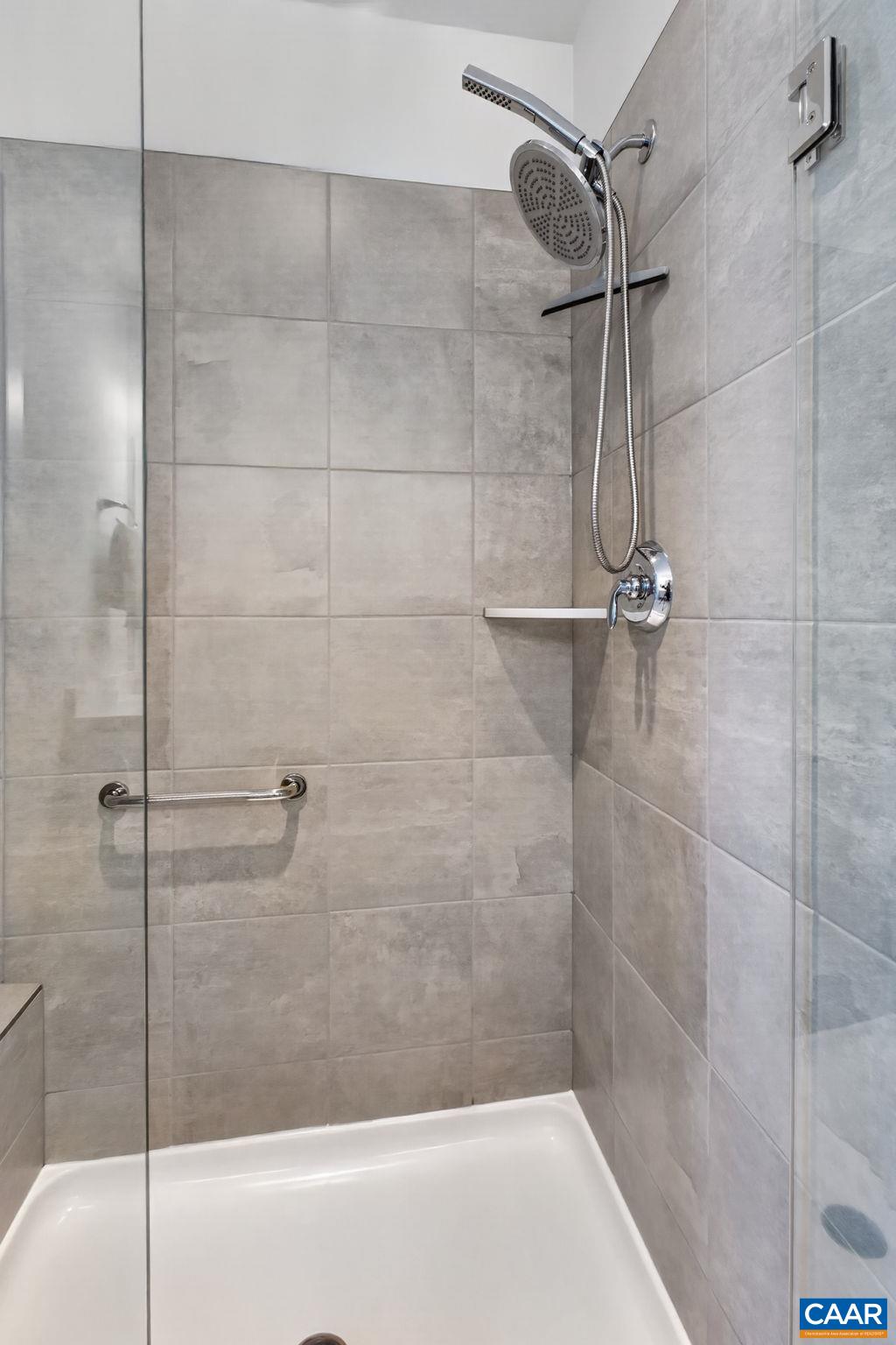 Large primary tiled shower with bench seat and multiple shower heads. Large primary tiled shower with bench seat and multiple shower heads.