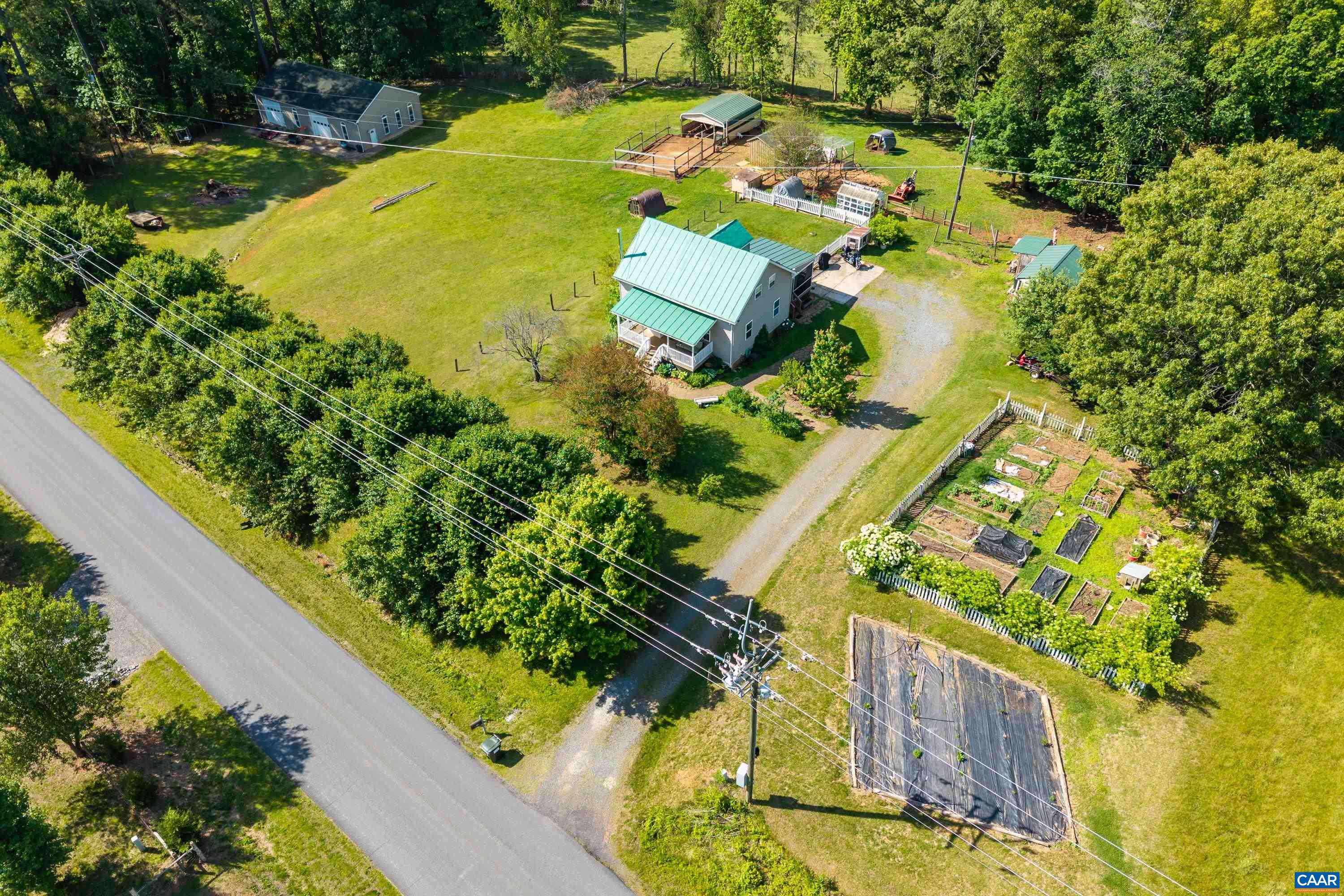 Aerial view showcasing the established homestead setting with home, outbuildings, garden areas, and open green space surrounded by countryside. Aerial view showcasing the established homestead setting with home, outbuildings, garden areas, and open green space surrounded by countryside.