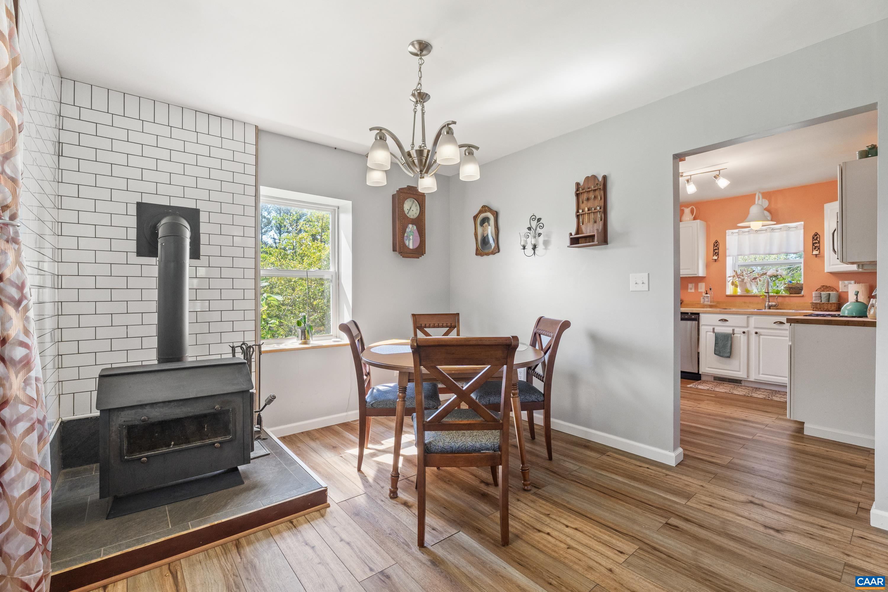 Dining area with wood stove, chandelier, and open flow into the kitchen. Dining area with wood stove, chandelier, and open flow into the kitchen.