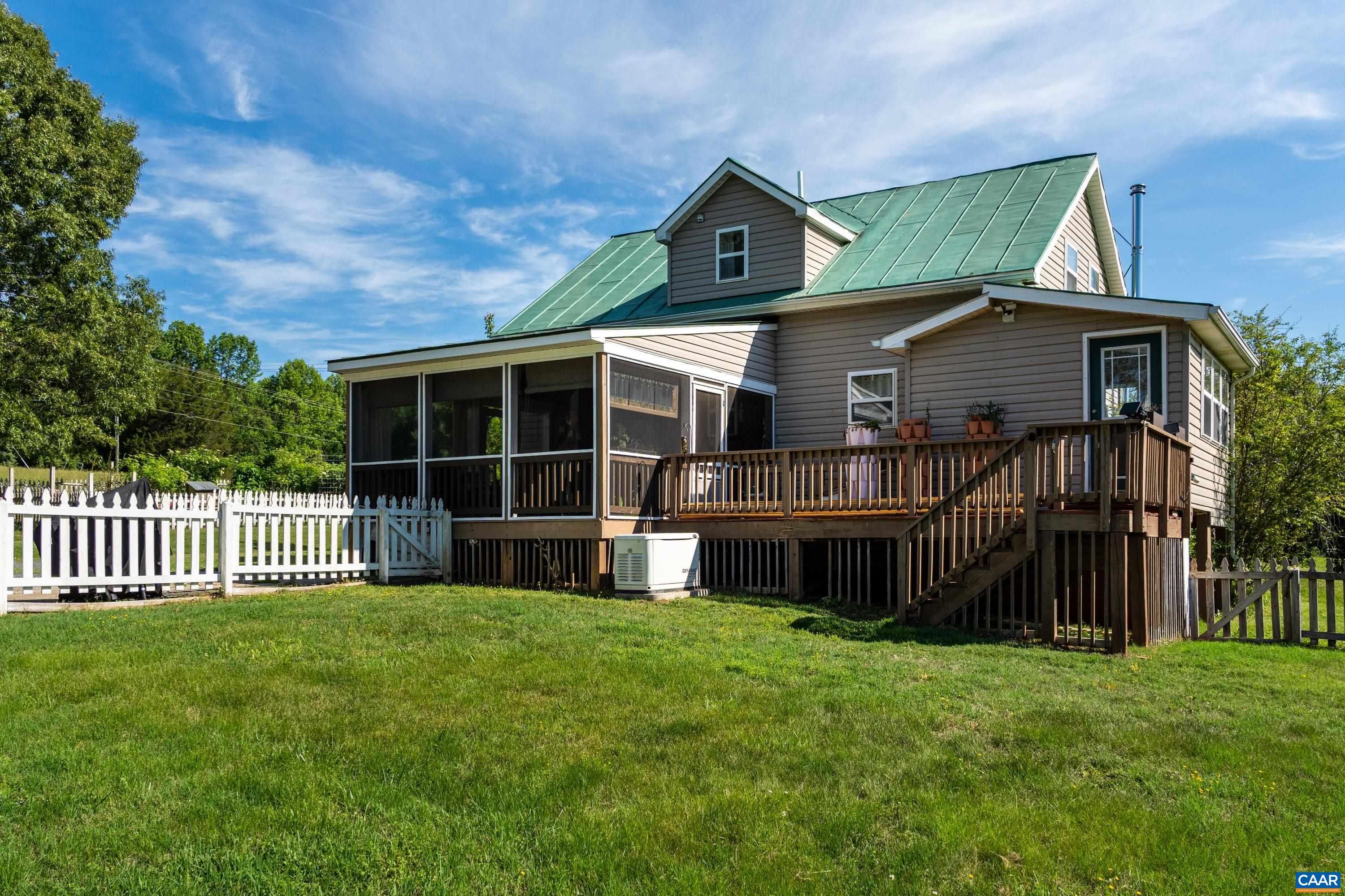 Rear exterior view showing the home’s whole home generator, elevated setting, covered porch area, and fenced yard space. Rear exterior view showing the home’s whole home generator, elevated setting, covered porch area, and fenced yard space.