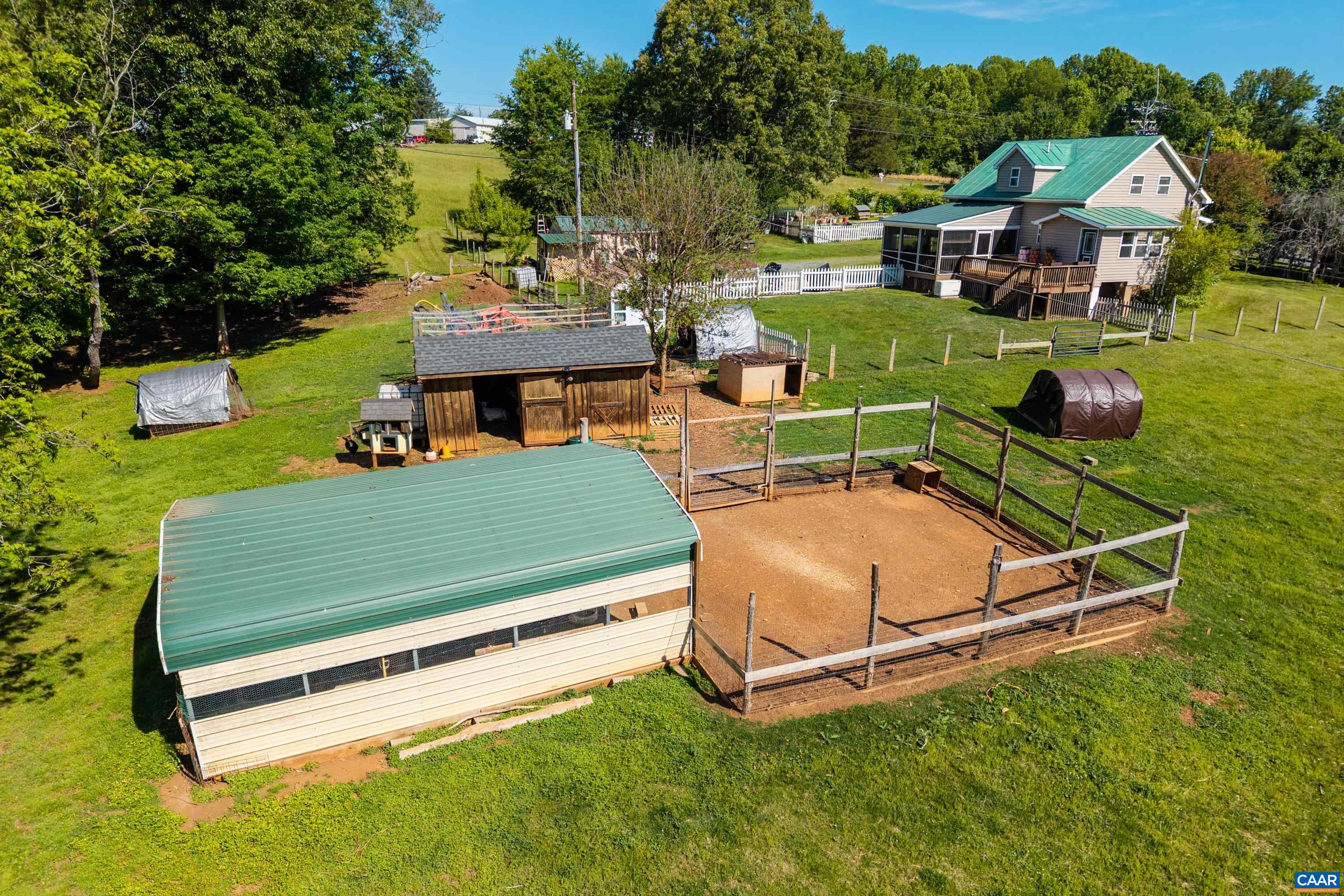 Fenced livestock pen with large covered shelter and other outbuildings ready to support homestead animal care. Fenced livestock pen with large covered shelter and other outbuildings ready to support homestead animal care.