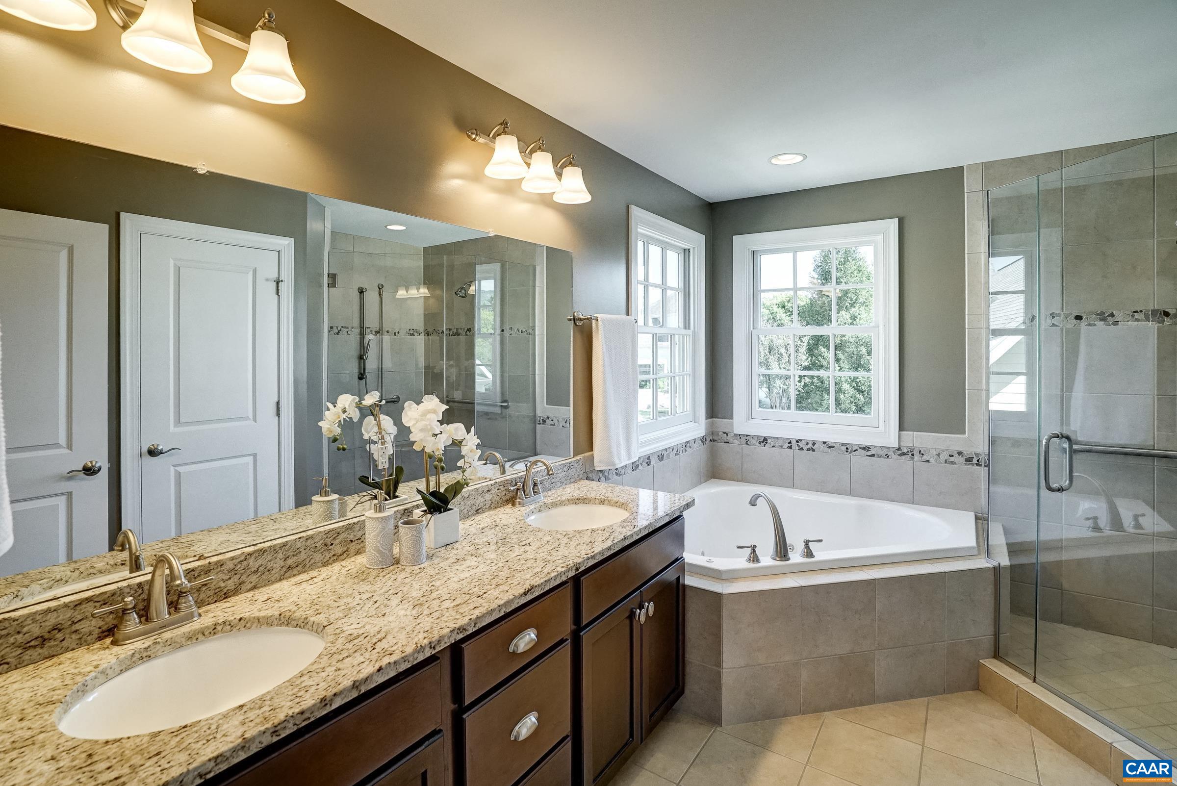Primary bathroom with jetted soaking tub and frameless glass shower.