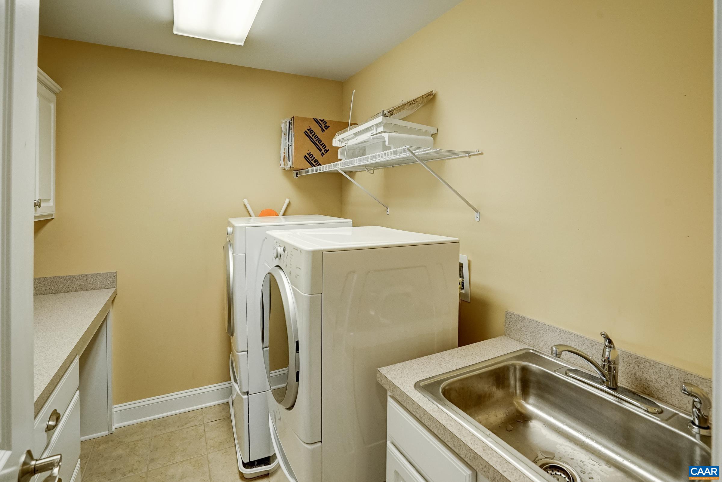 Second floor laundry with utility sink and cabinets.