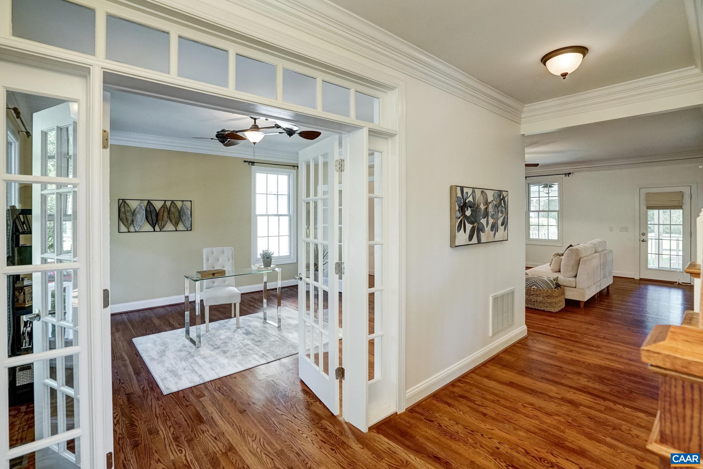 Home office to the left of the foyer features glass french doors with transom.