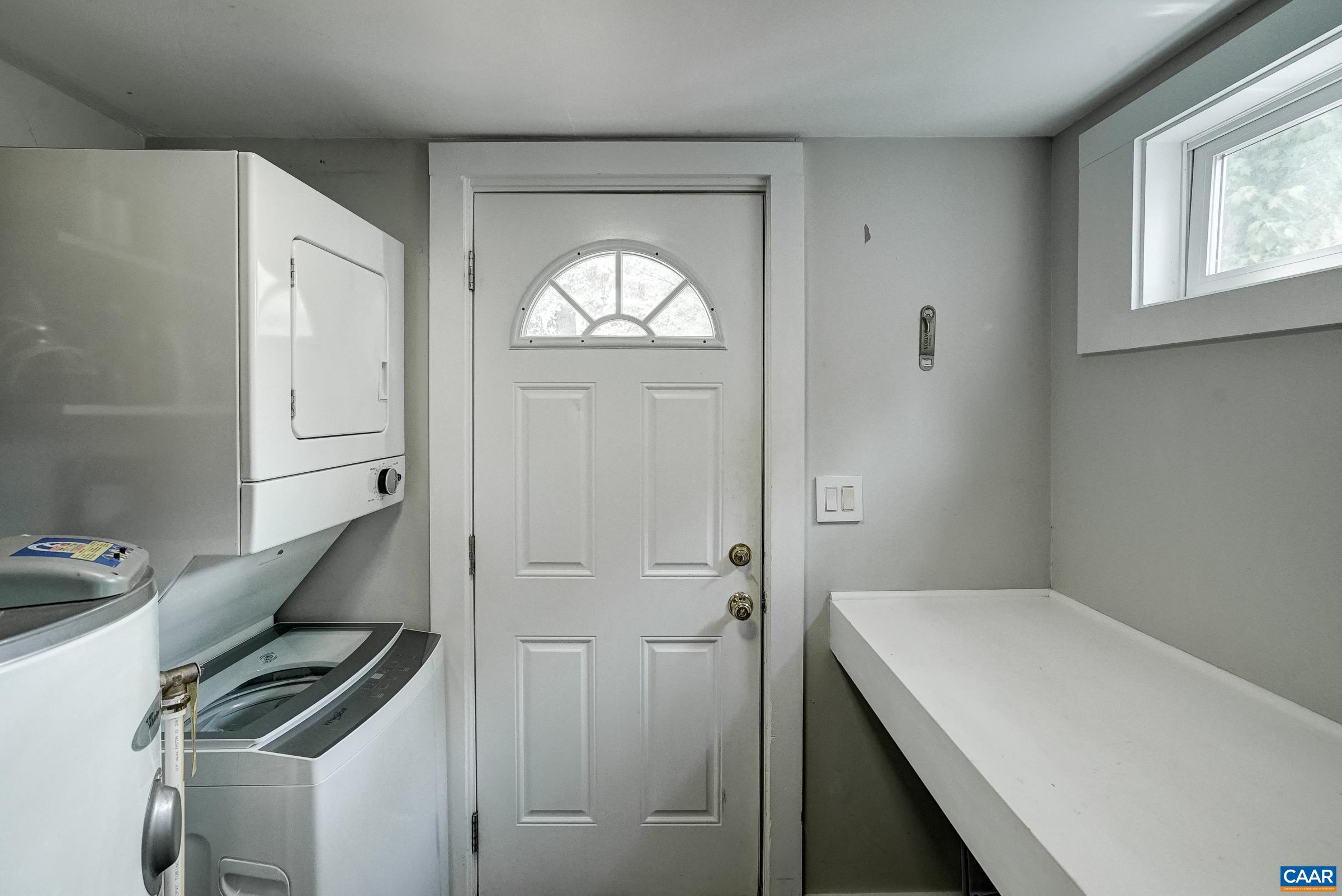 Utility room with stacked washer/dryer and folding area.