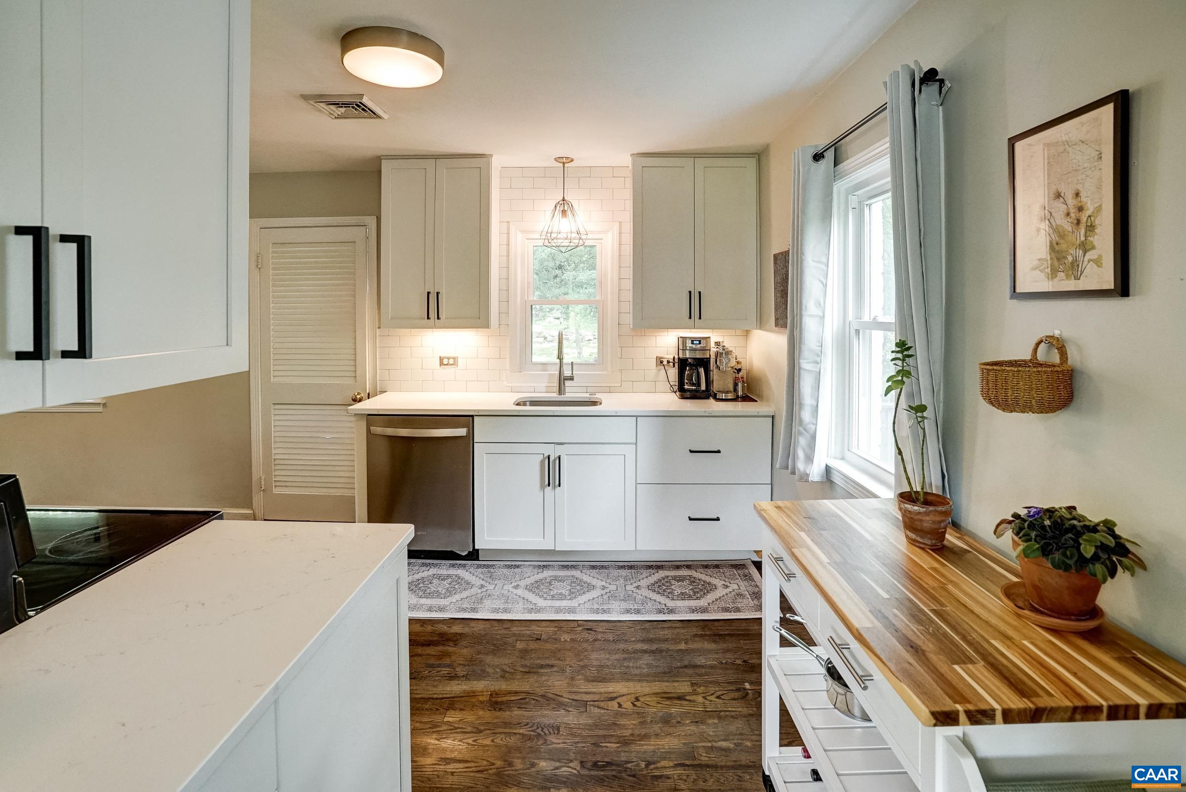 Updated kitchen features white cabinets with tile backsplash and quartz counters.