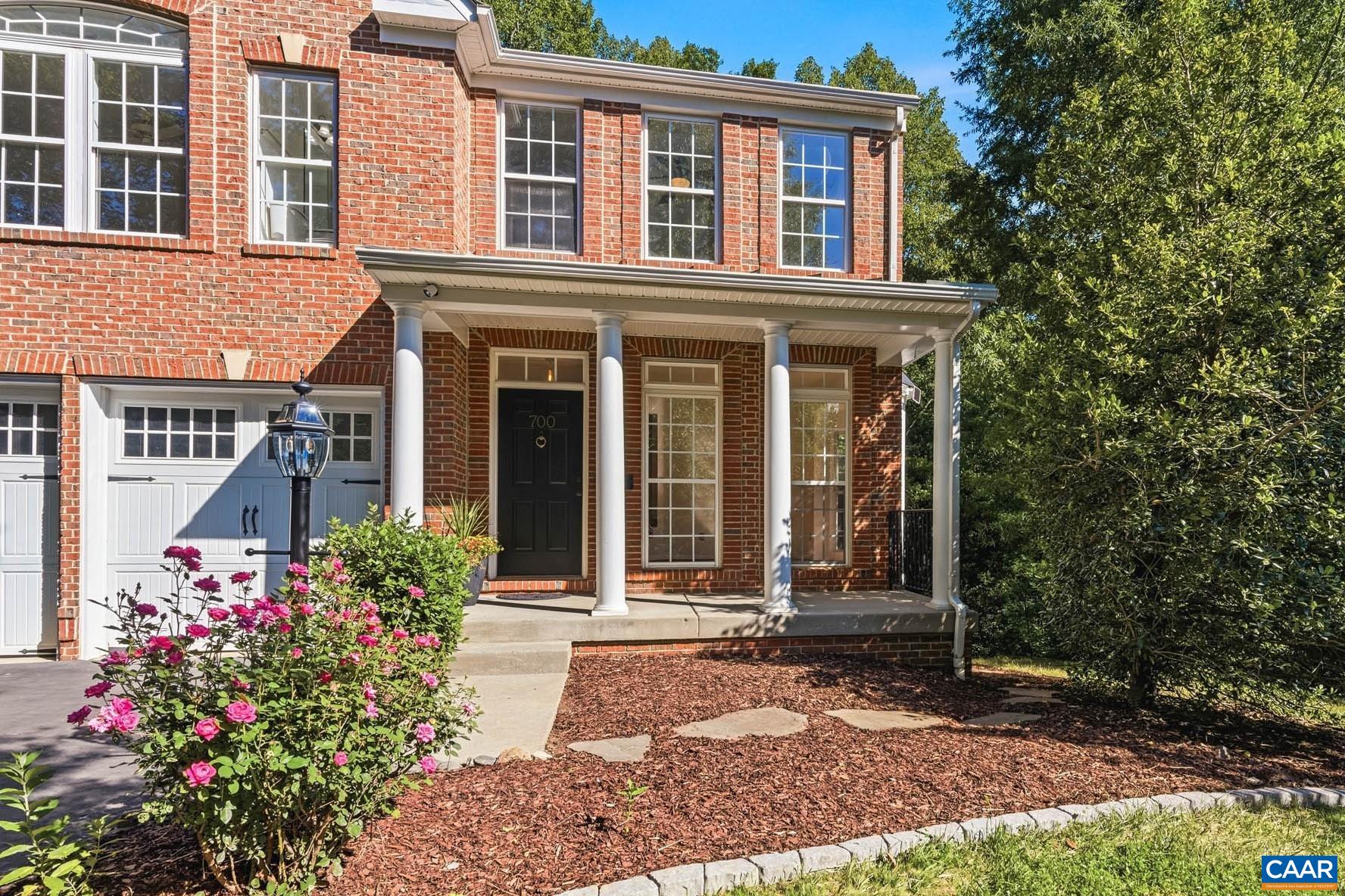 A closer look at the welcoming front porch with flowering landscape beds and shaded entry.