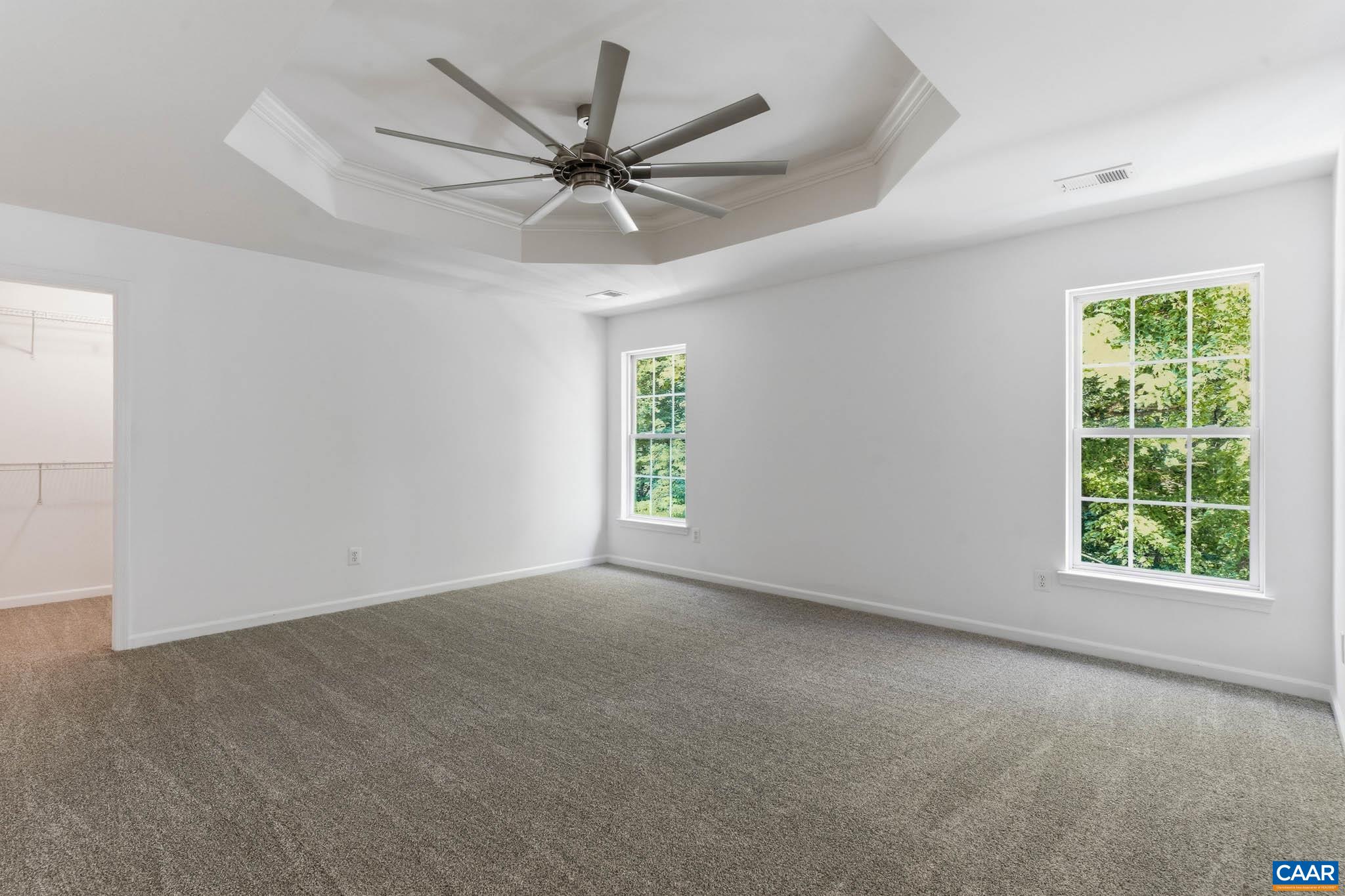 Spacious primary bedroom with tall windows, natural light, and room for a full bedroom setup with spacious walk in closet.