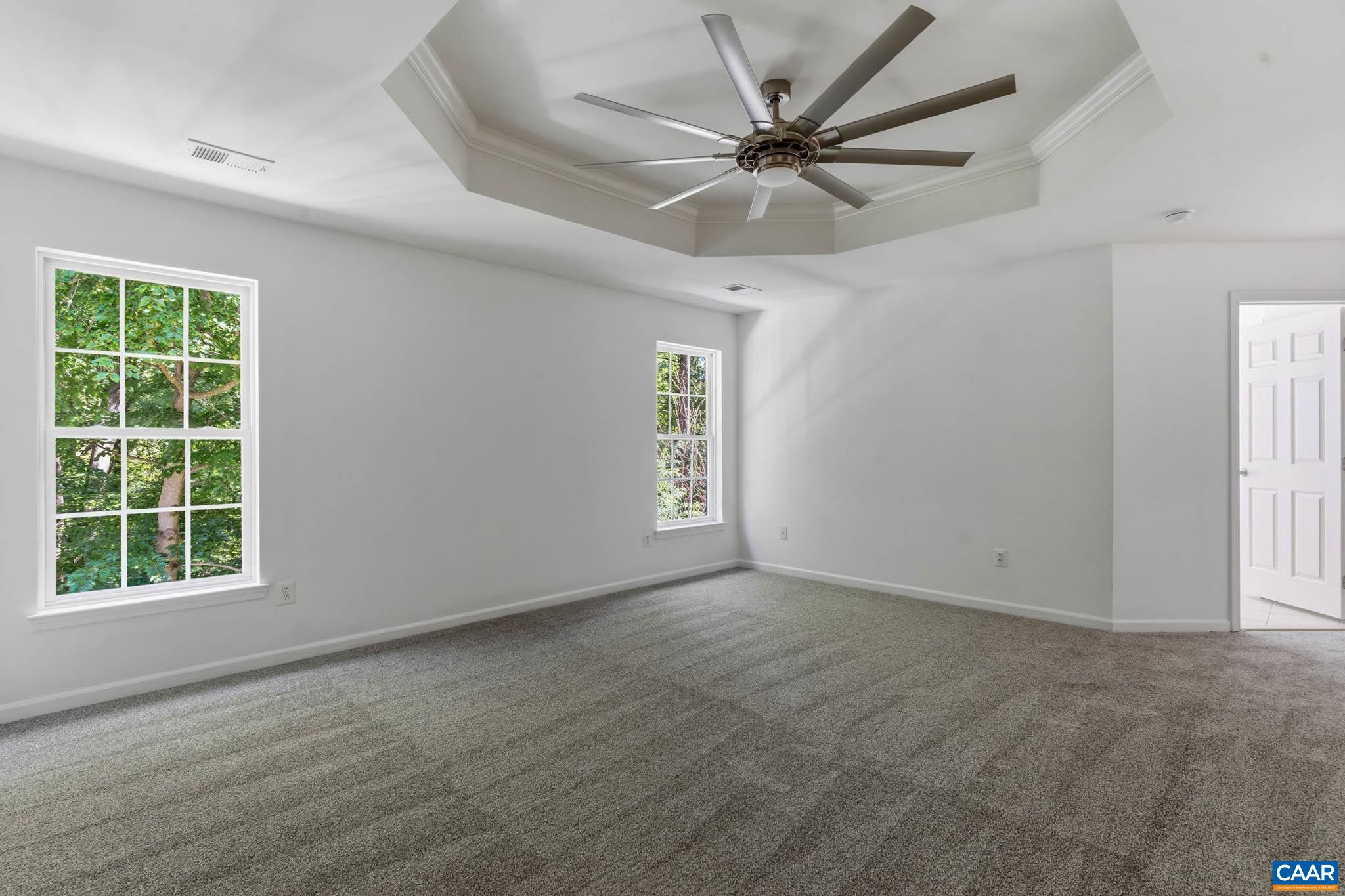 Spacious primary bedroom with tall windows, natural light, and room for a full bedroom setup and private access to the ensuite primary bathroom.
