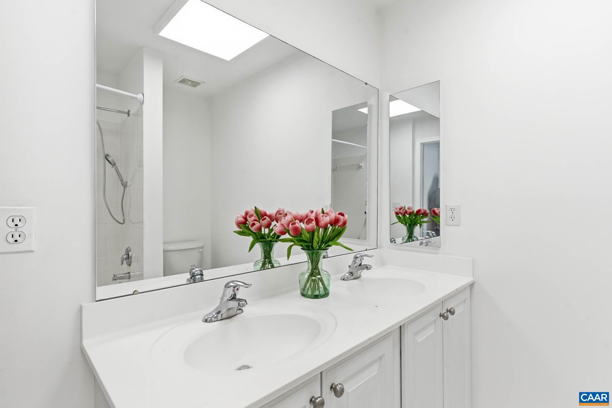 Clean hall bath with dual sink vanity and tub/shower shared by secondary bedrooms two and three.