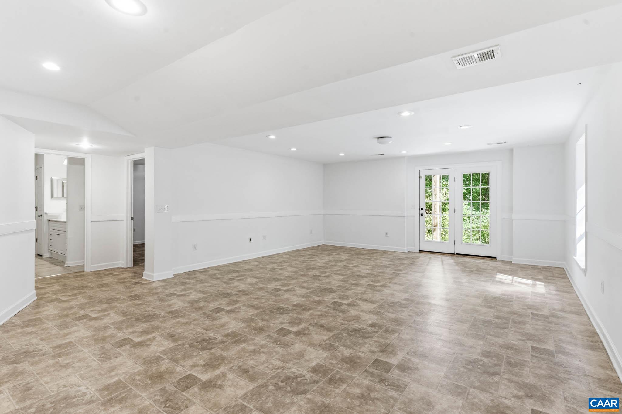 Expansive finished basement with extra tall ceilings, bedroom and full bath, with French doors to the rear exterior.