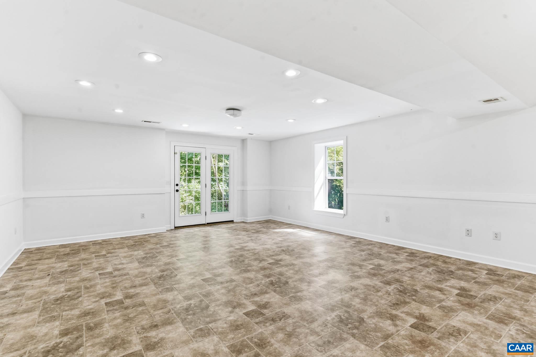 Expansive finished basement with extra tall ceilings with French doors to the rear exterior.