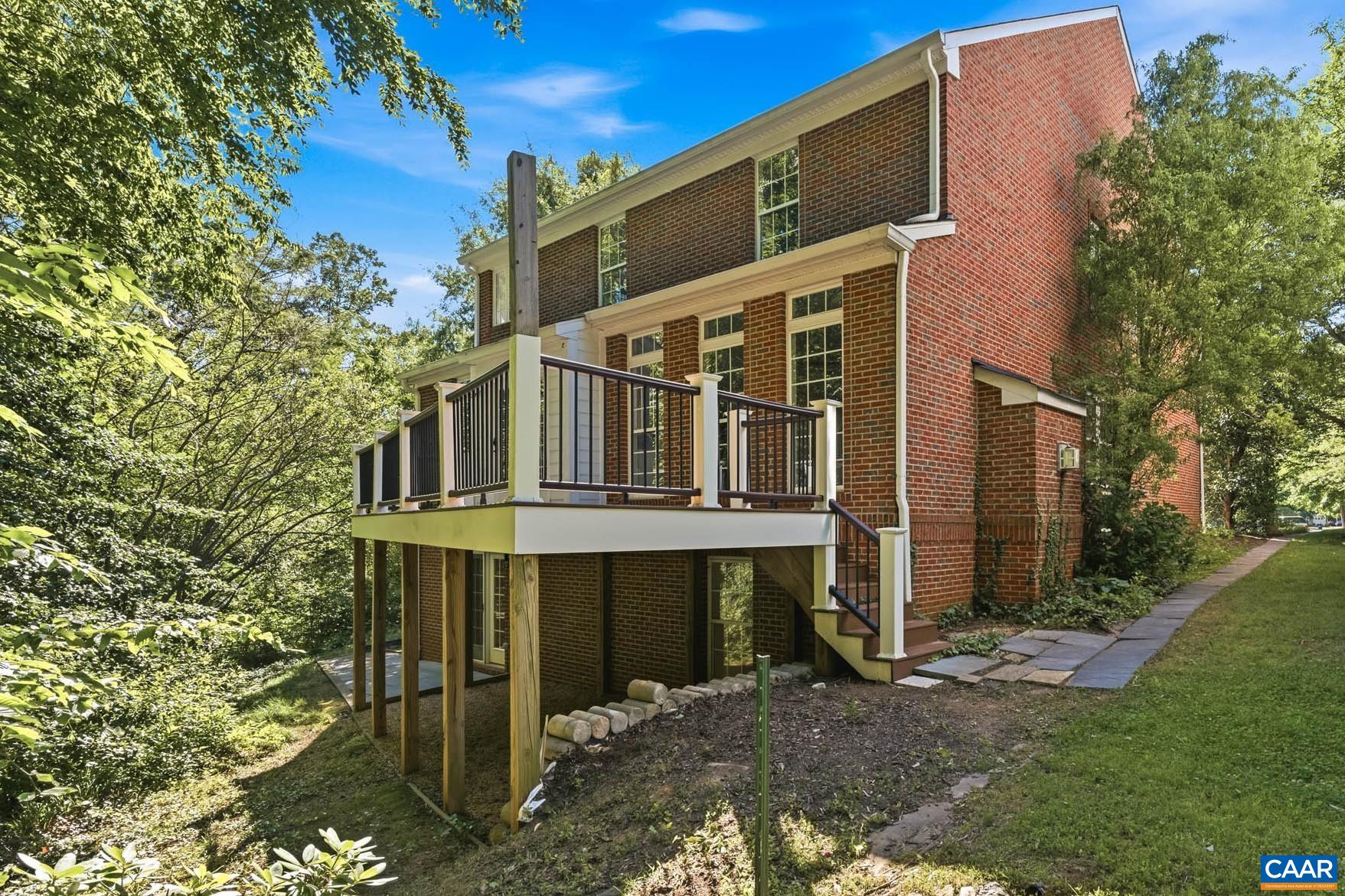 Rear view showing how the deck, terrace, and wooded setting work together.