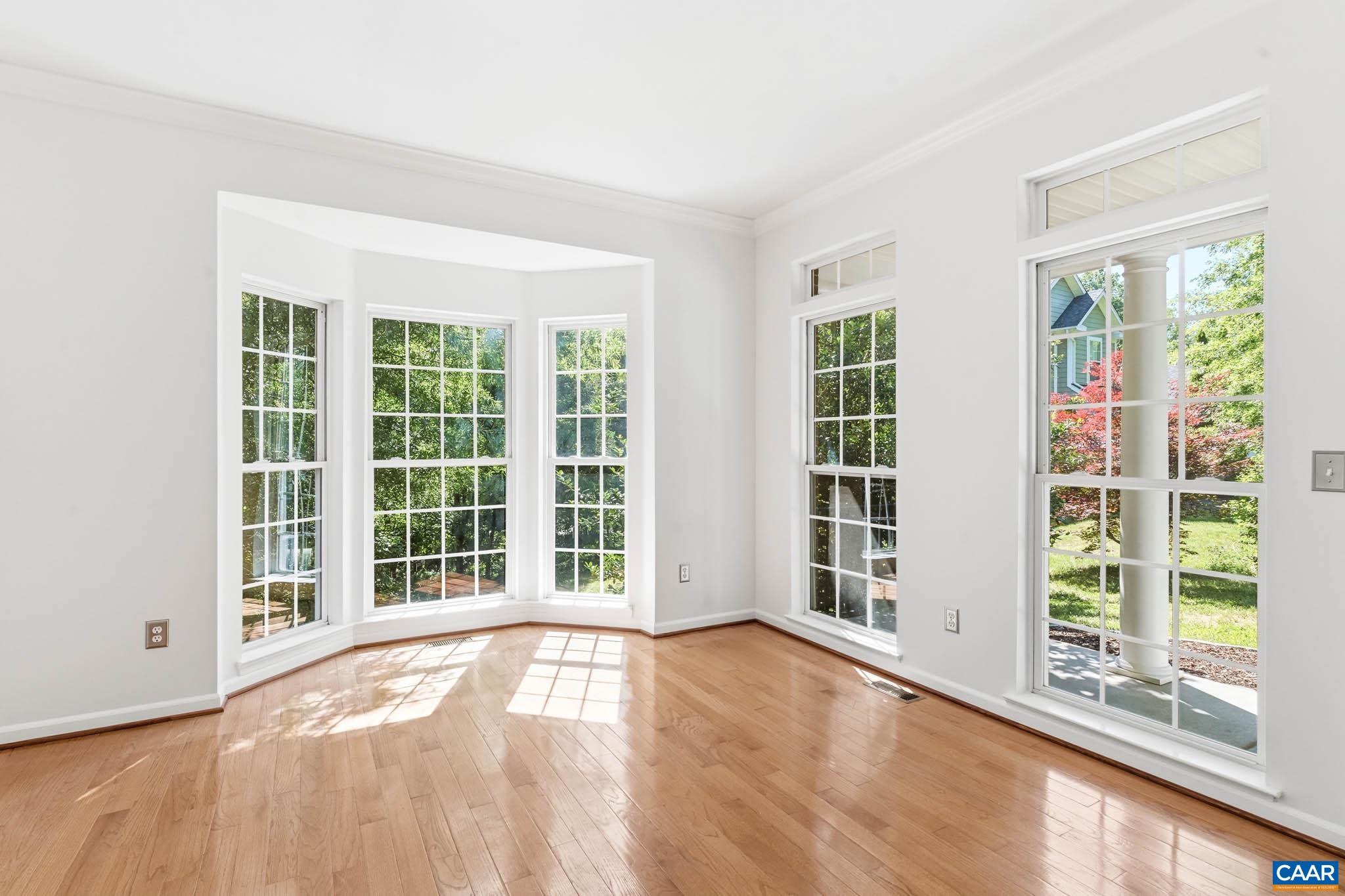 Bright front living space with hardwood floors and tall windows.