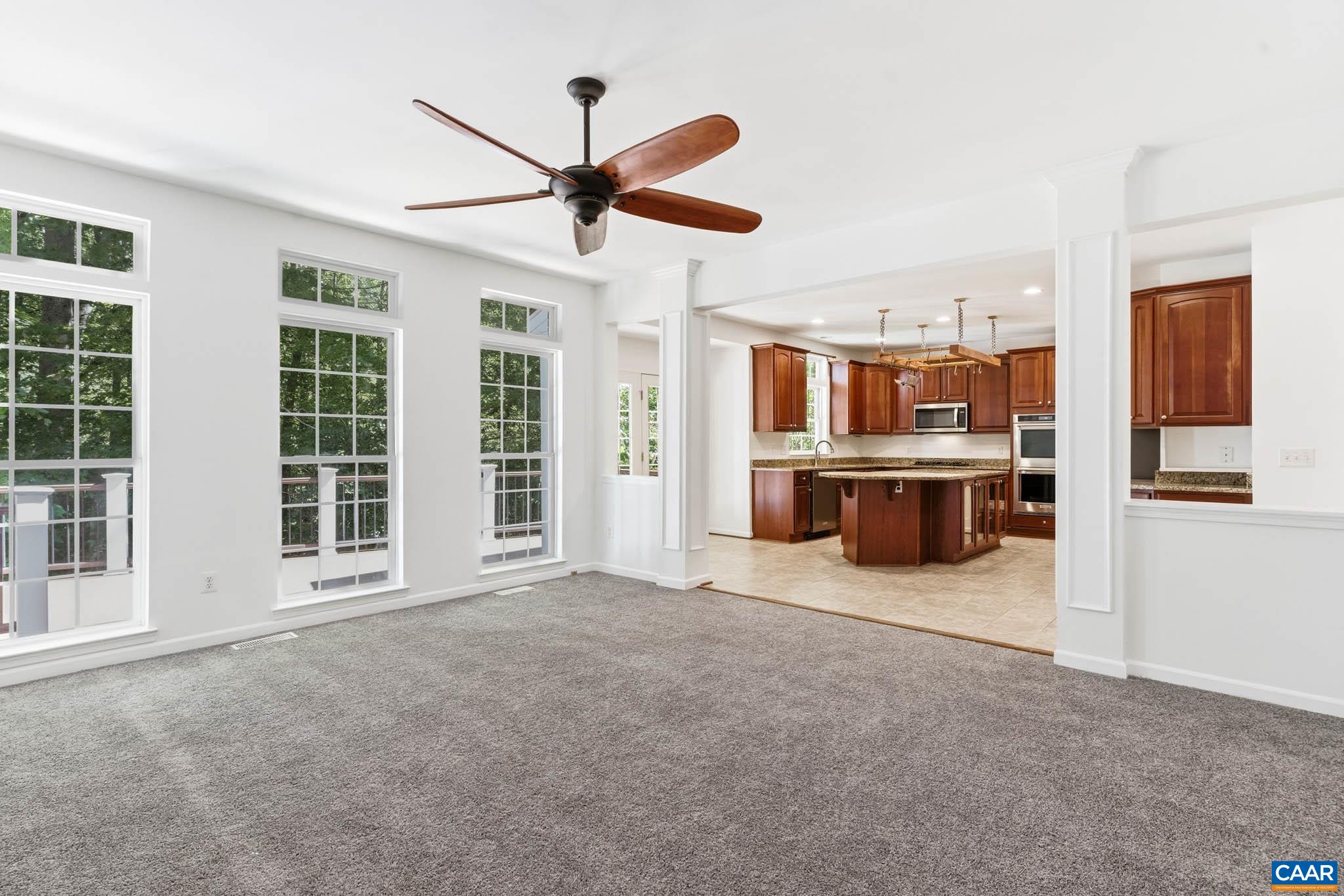 Open sightlines between the family room, kitchen, back deck, and wooded rear views.