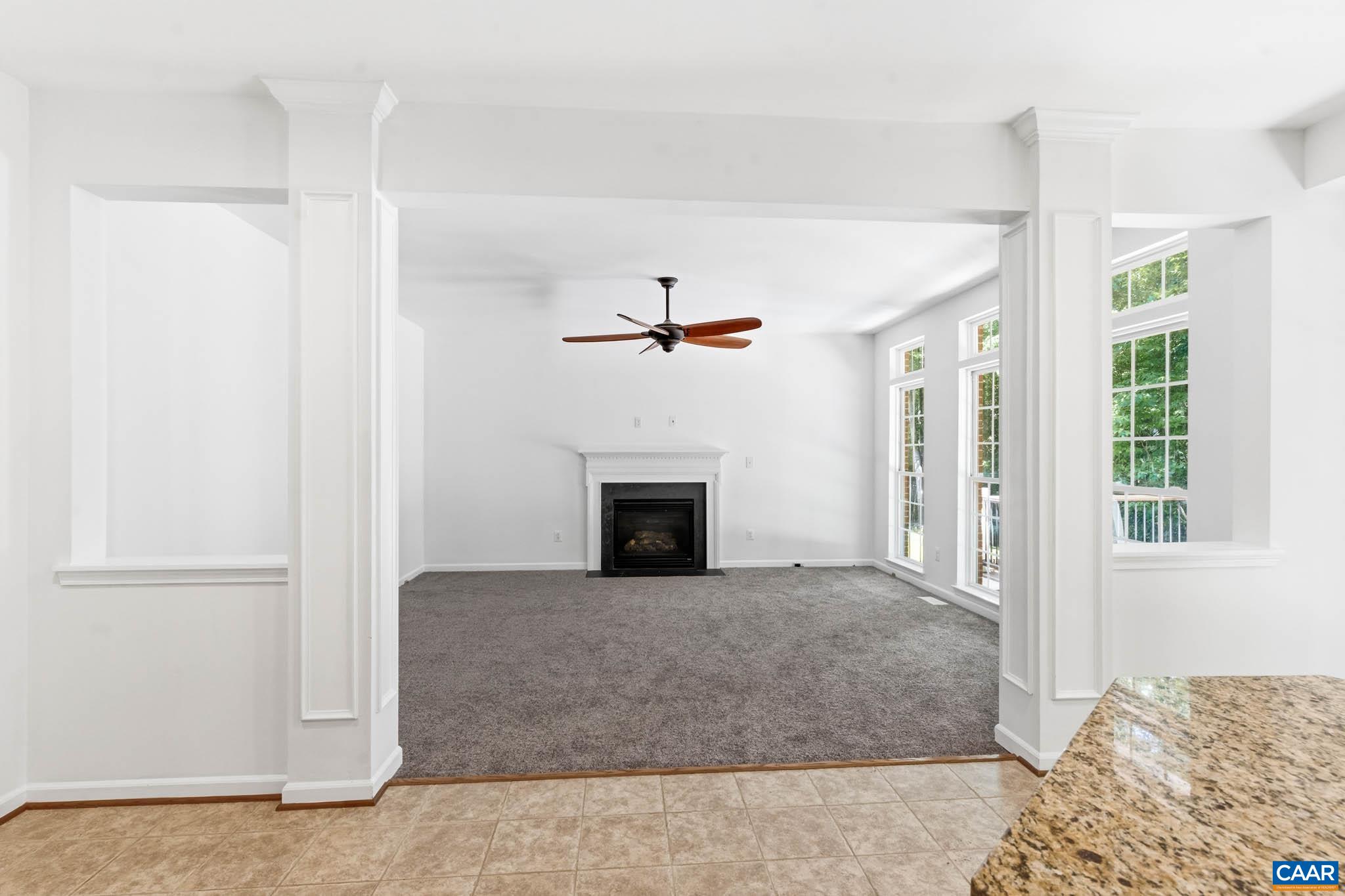 Comfortable rear living area with fireplace, tall windows, deck views, and direct connection to the kitchen.