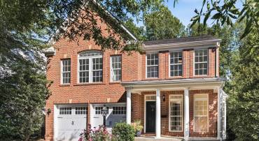 A stately brick exterior, one of two brick detached homes in the neighborhood, framed by mature landscaping.