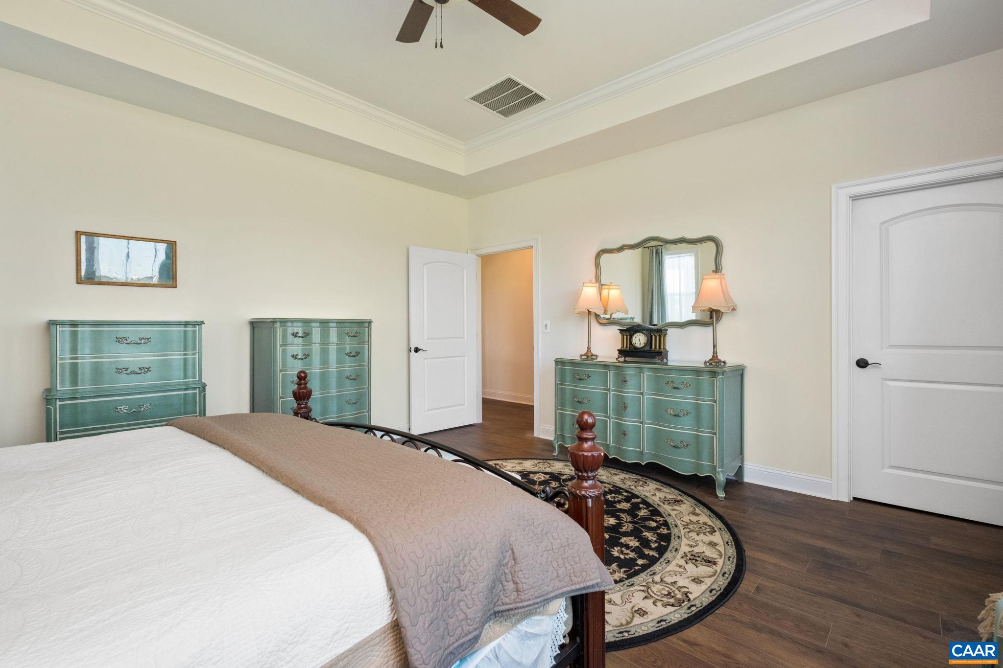 Located on the first floor, with plenty of windows for natural light, a tray ceiling, and a large ensuite bathroom. The primary suite hallway is in view, and ensuite bathroom is across the hallway. Located on the first floor, with plenty of windows for natural light, a tray ceiling, and a large ensuite bathroom. The primary suite hallway is in view, and ensuite bathroom is across the hallway.