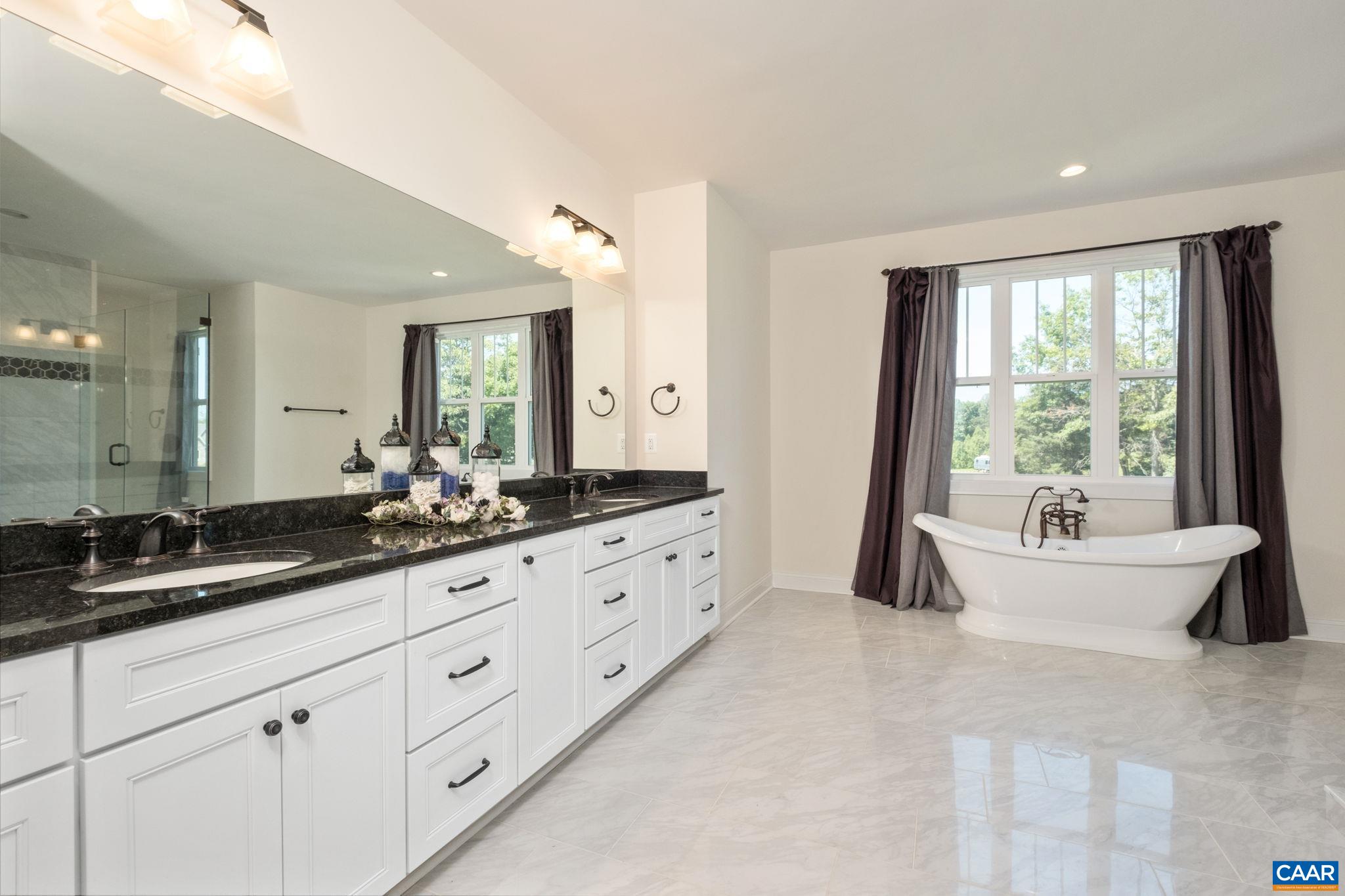 The ensuite bathroom is sizable, with a large granite counter and dual sinks, porcelain tile floor, garden tub, and a large tiled shower. The ensuite bathroom is sizable, with a large granite counter and dual sinks, porcelain tile floor, garden tub, and a large tiled shower.