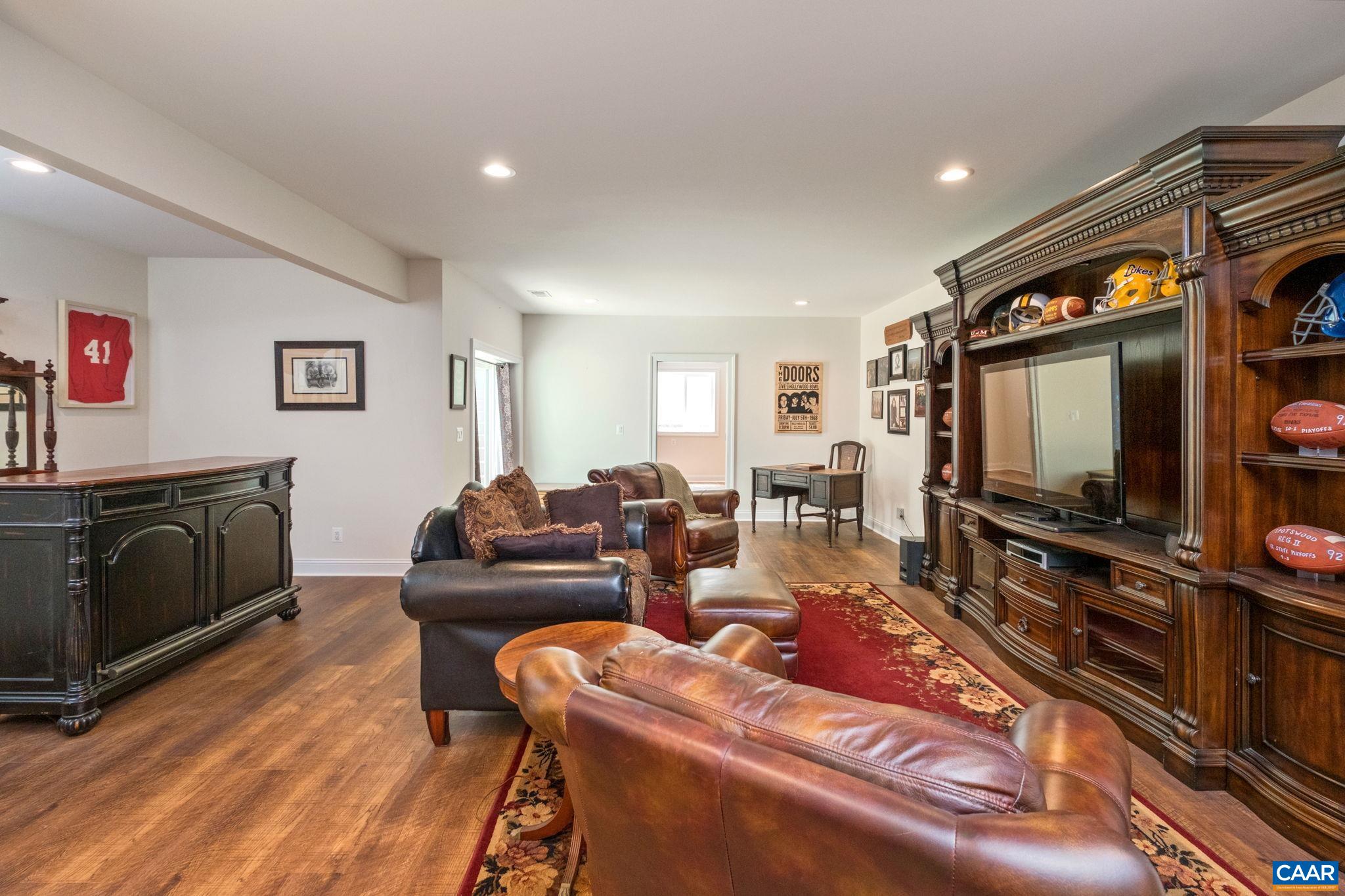 This section of the basement living room/den has a seating area and a large TV console/ entertainment center. The bar area is just behind the seating area. This section of the basement living room/den has a seating area and a large TV console/ entertainment center. The bar area is just behind the seating area.