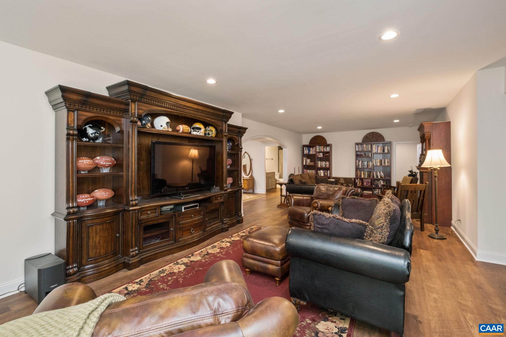 This section of the living room/den has a seating area and a large TV console/ entertainment center. The bar area is just behind the seating area. This section of the living room/den has a seating area and a large TV console/ entertainment center. The bar area is just behind the seating area.