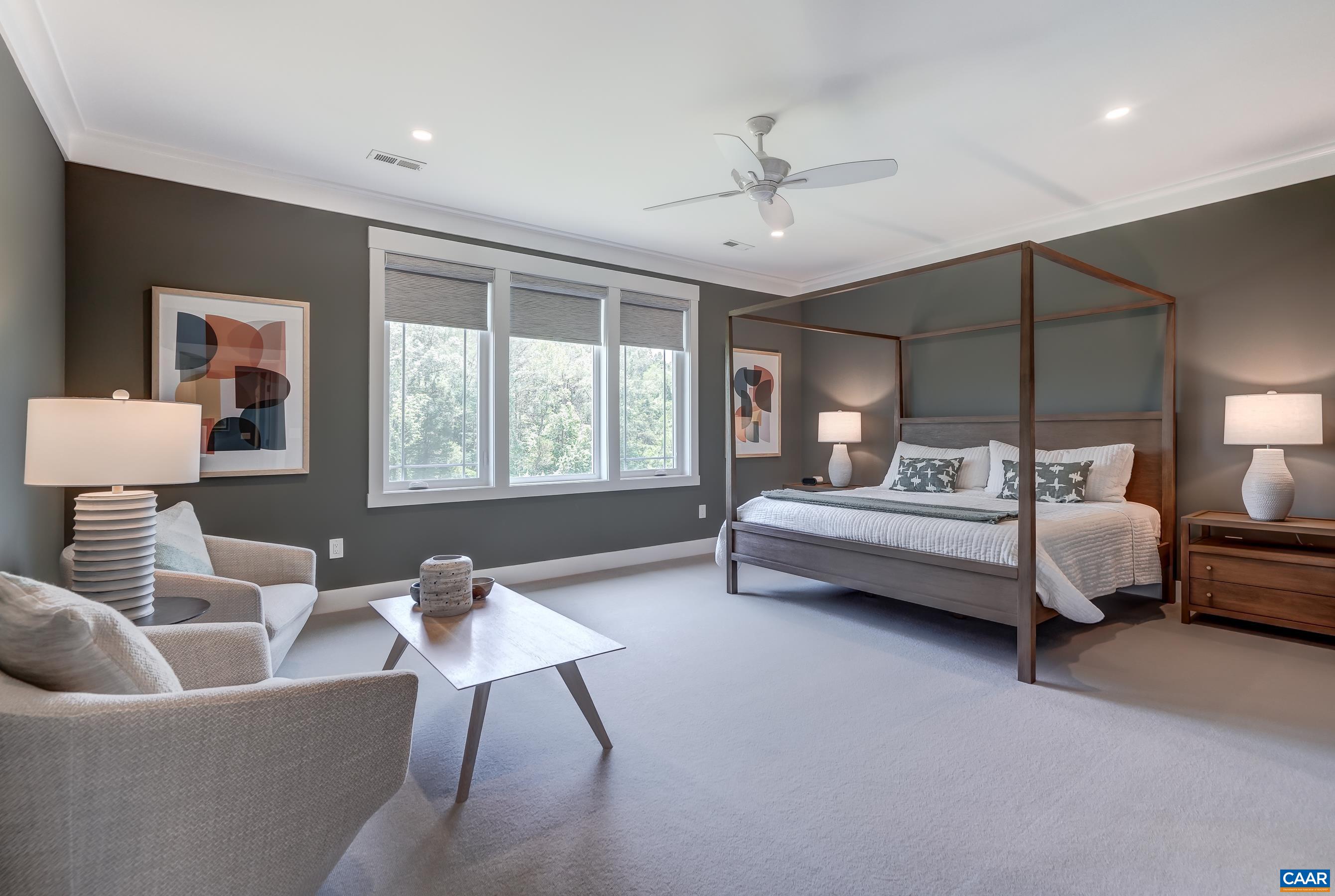 Main level primary suite with sitting area and ceiling fan. Main level primary suite with sitting area and ceiling fan.