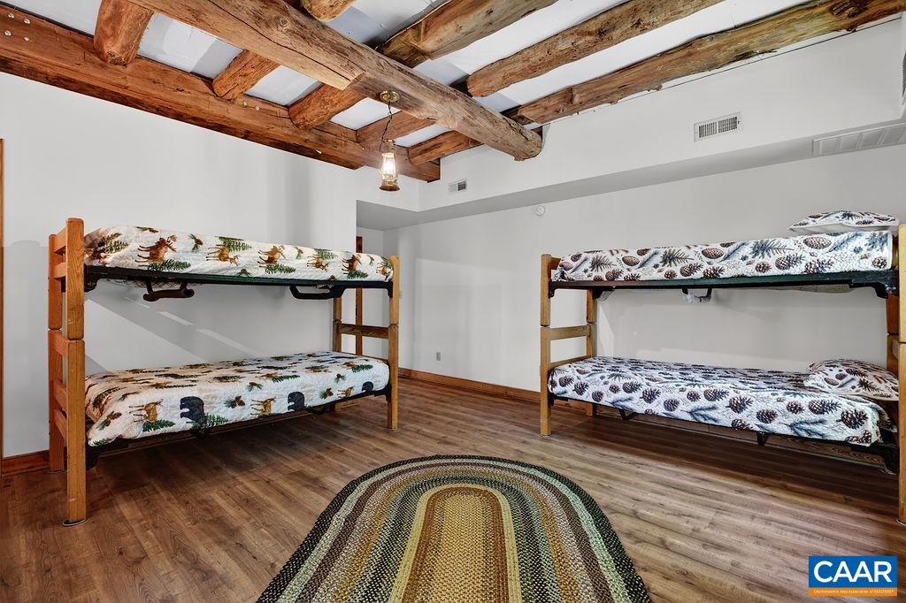 Notice the impressive hand-hewn beams overhead, adding historic character and architectural interest to this spacious lower-level bunk room. Notice the impressive hand-hewn beams overhead, adding historic character and architectural interest to this spacious lower-level bunk room.
