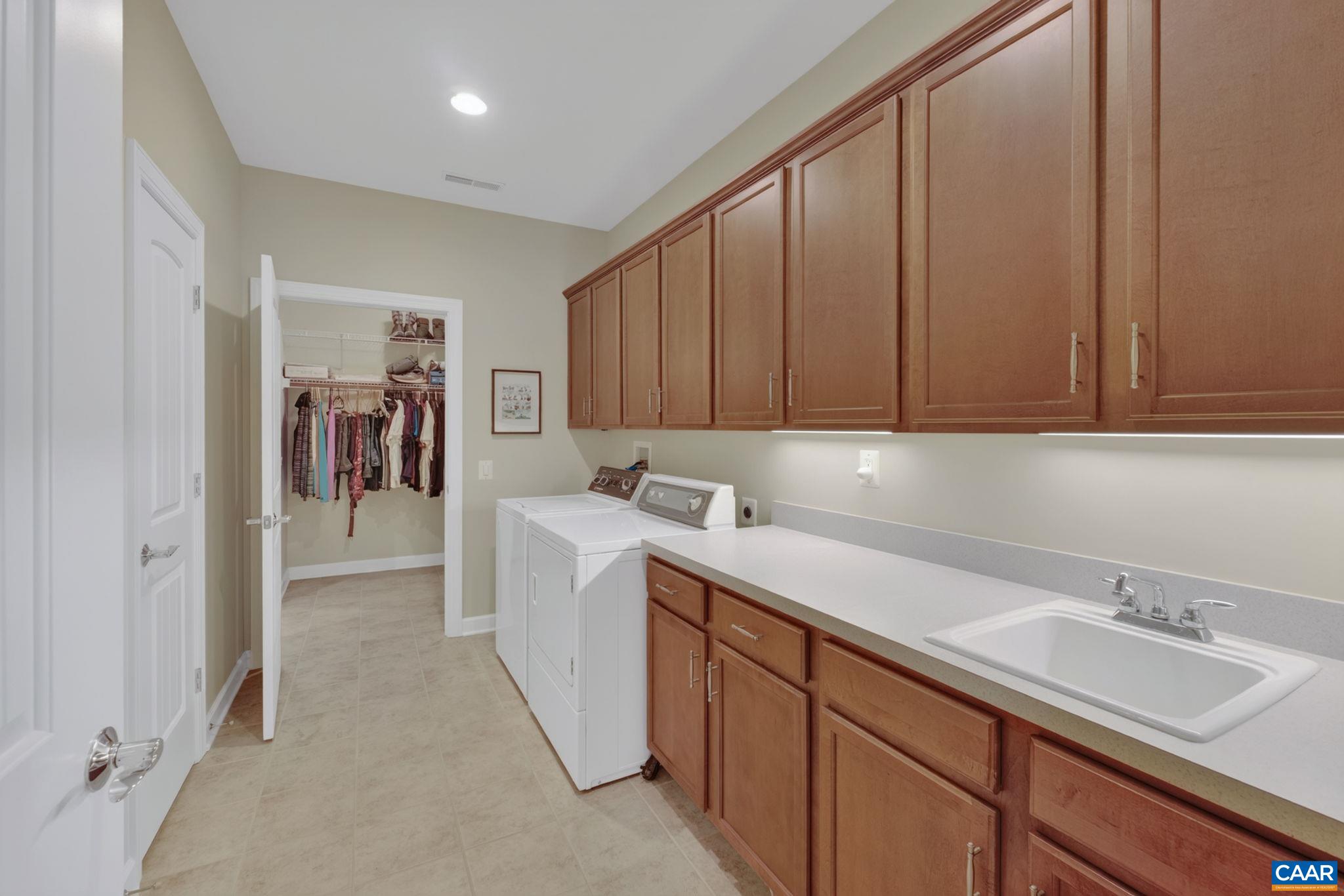 Laundry room with Speed Queen washer/dryer, counter space, storage and sink.