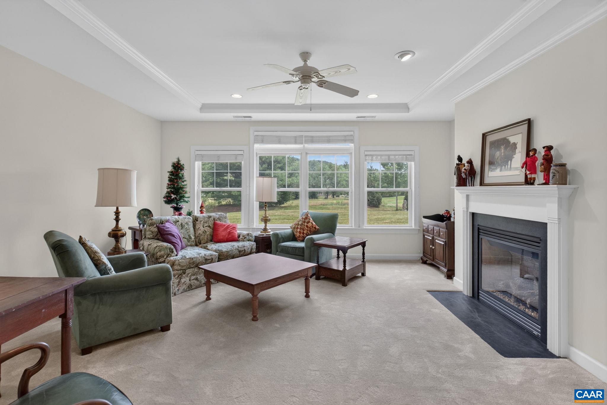 Large and bright living room with tray ceiling and gas fireplace.