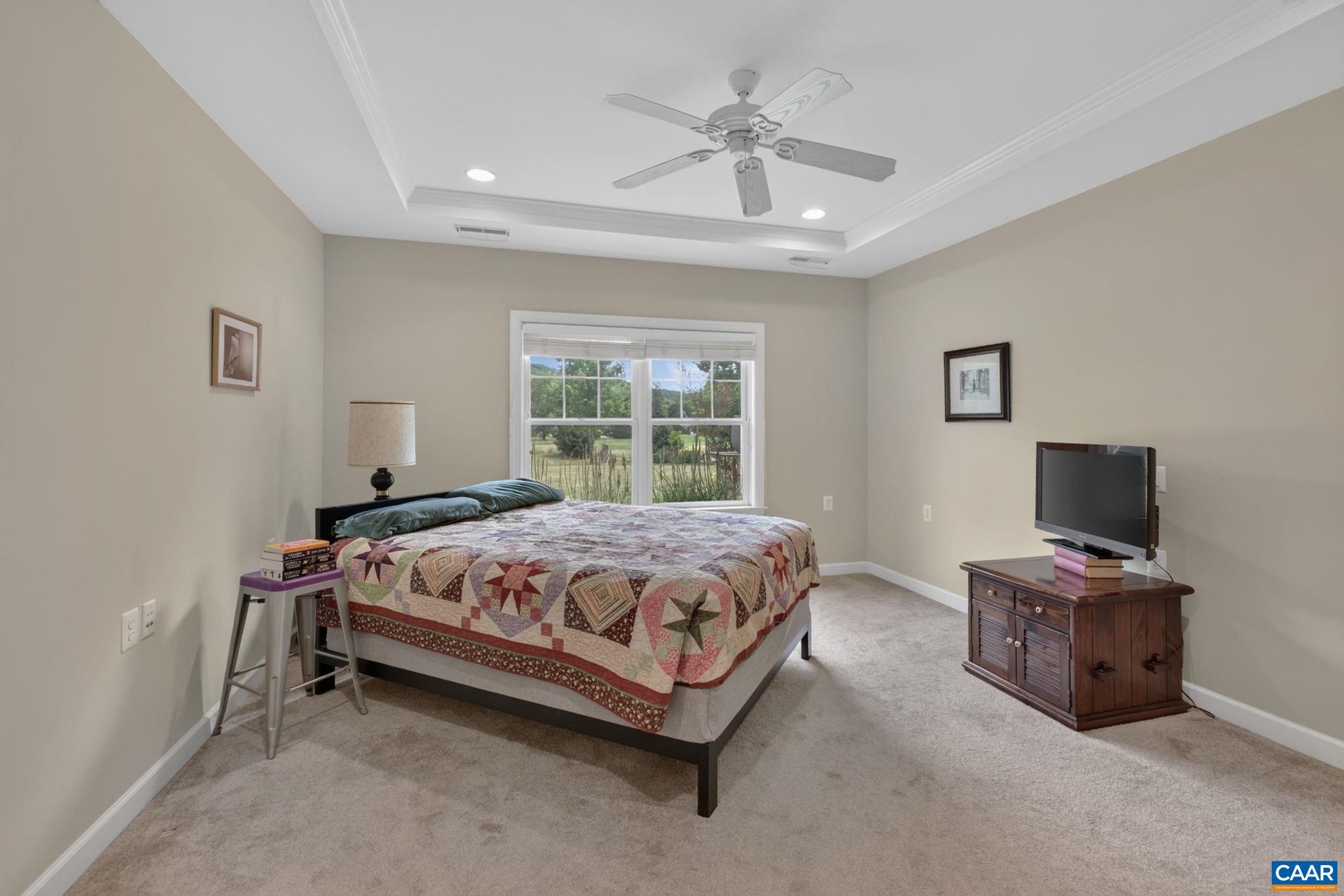 Large and bright primary bedroom with tray ceiling.