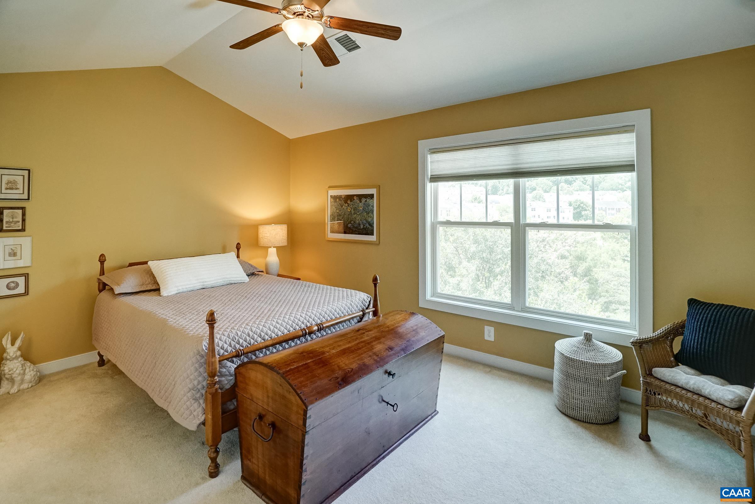 Vaulted primary suite features ceiling fan and light-filtering shades.