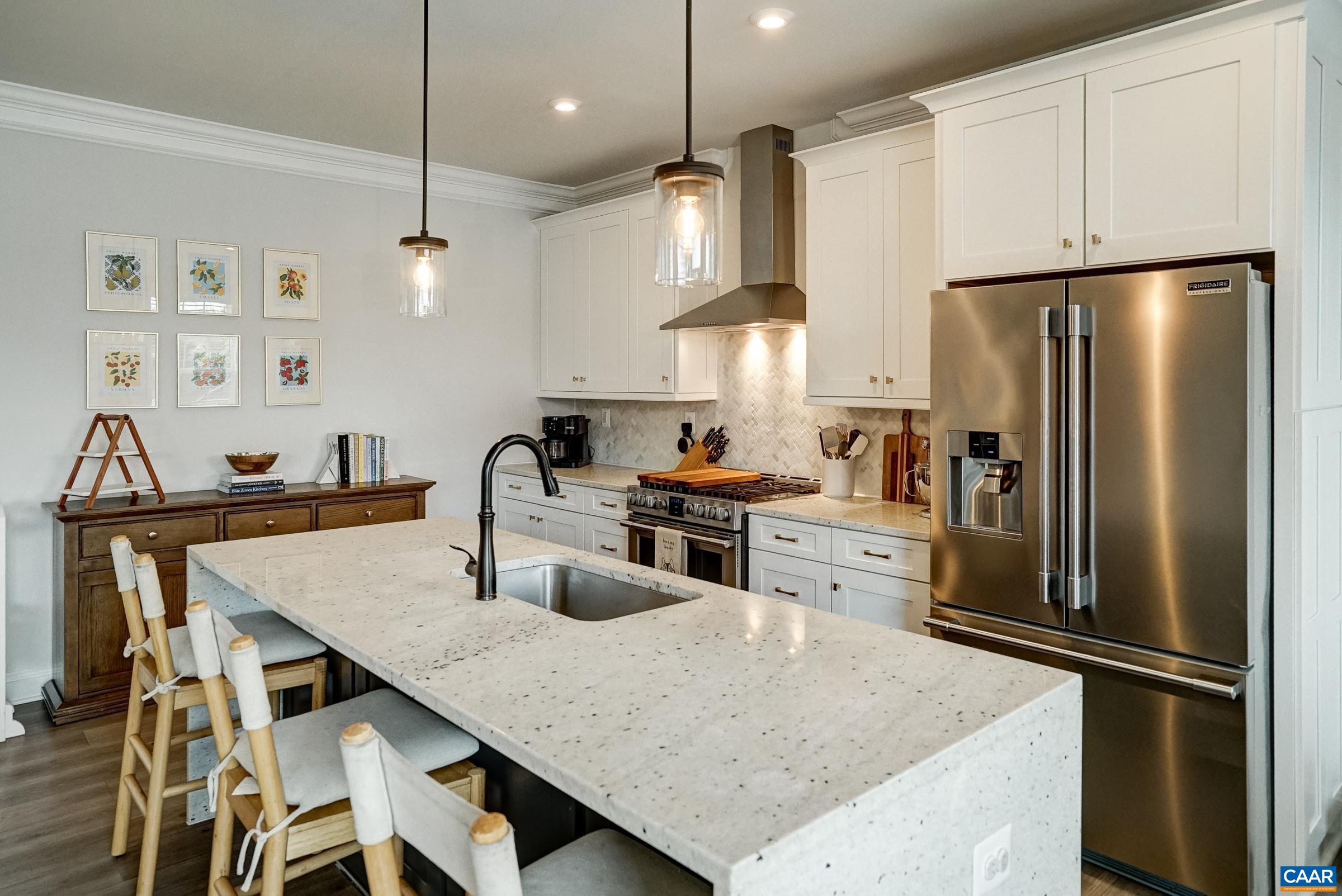 Gourmet kitchen features white cabinets and quartz waterfall counters
