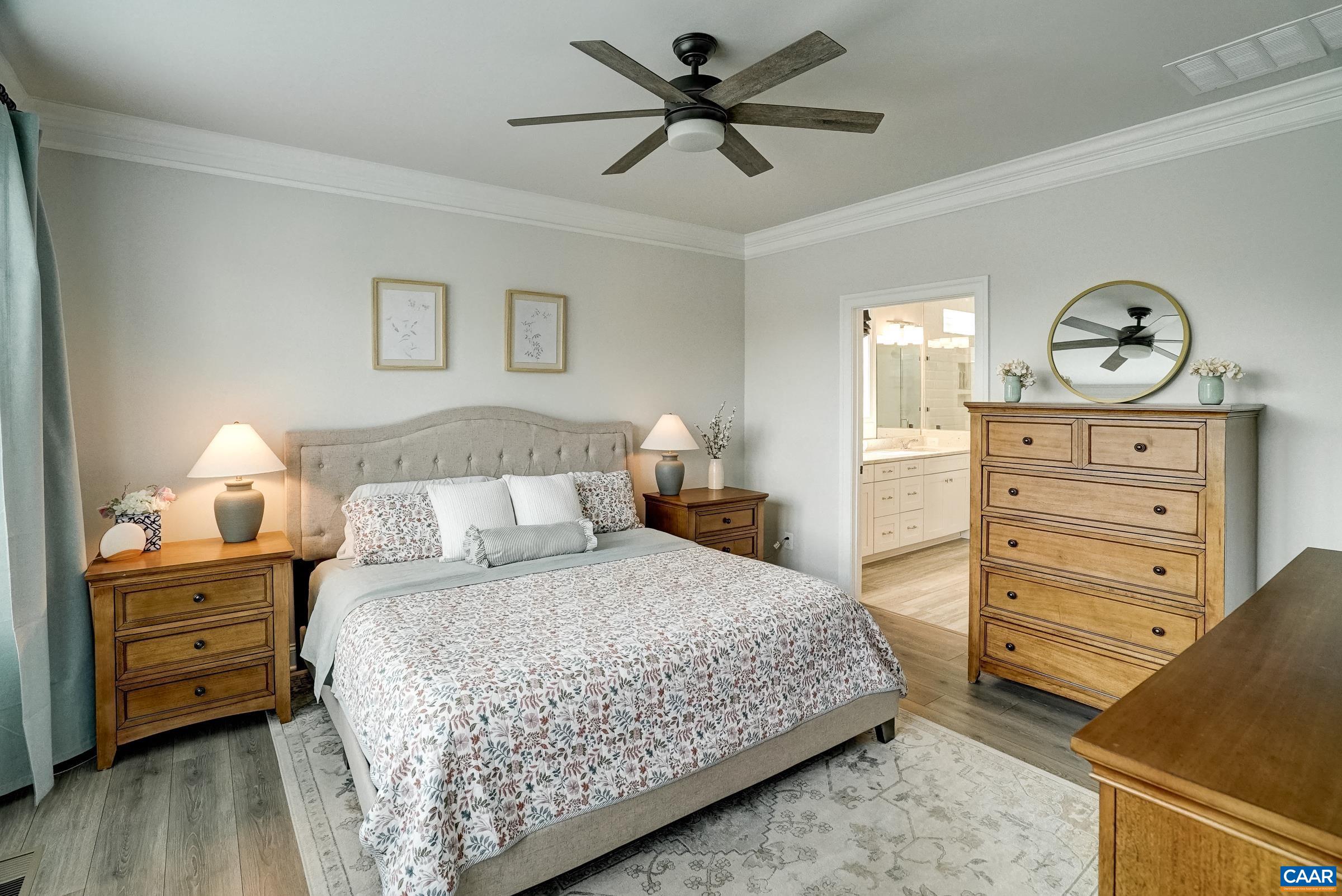 Primary bedroom features a ceiling fan and ensuite bathroom with walk-in closet.