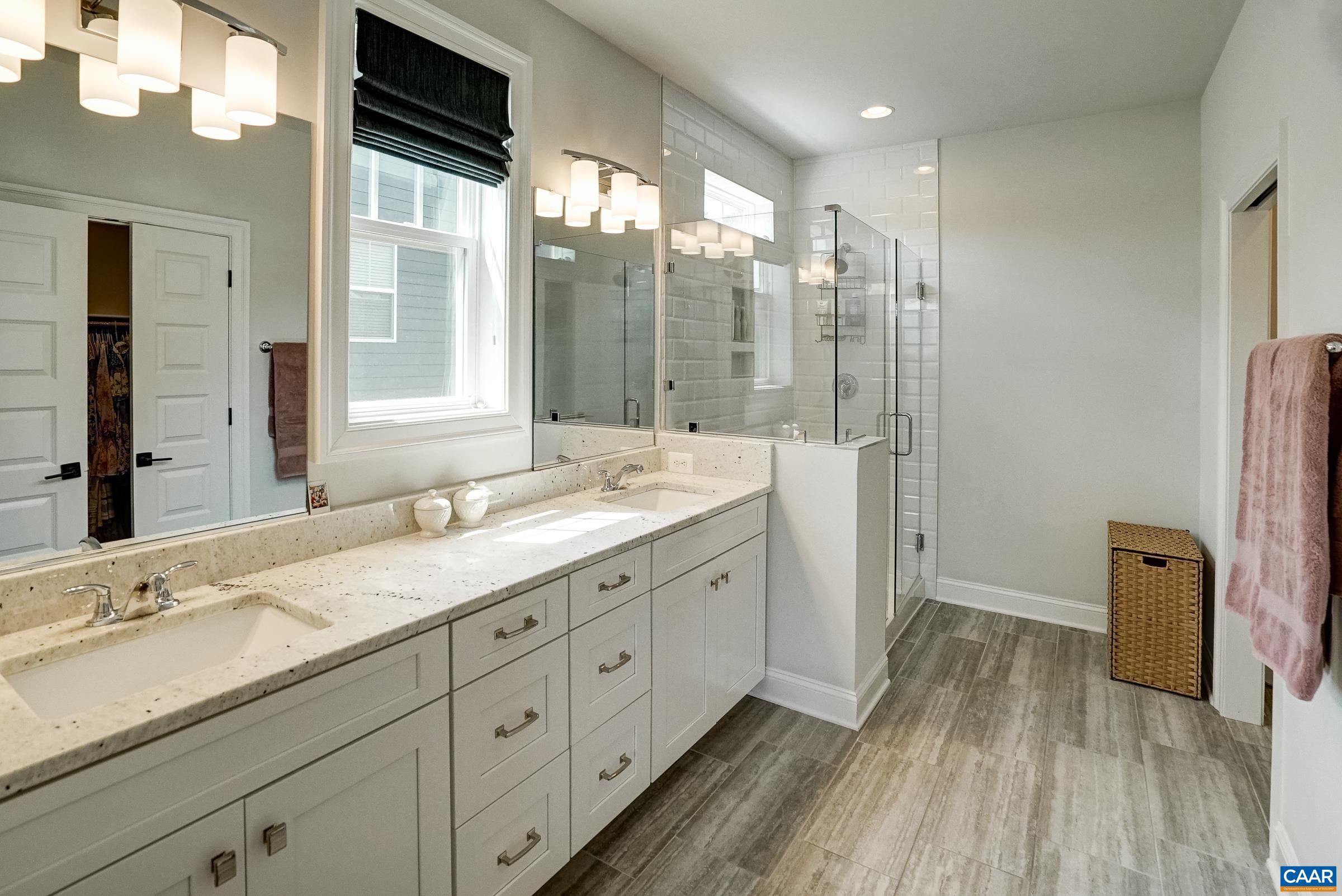 Primary bathroom features double sink vanity and frameless glass shower.
