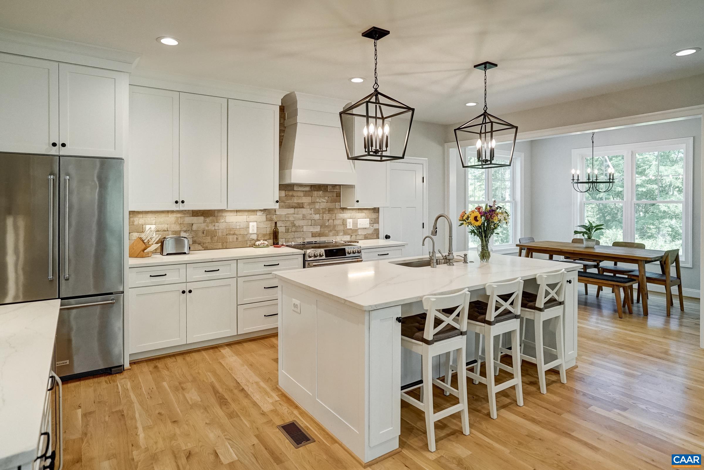 Gourmet kitchen features quartz countertops, white cabinets, and stainless appliances.