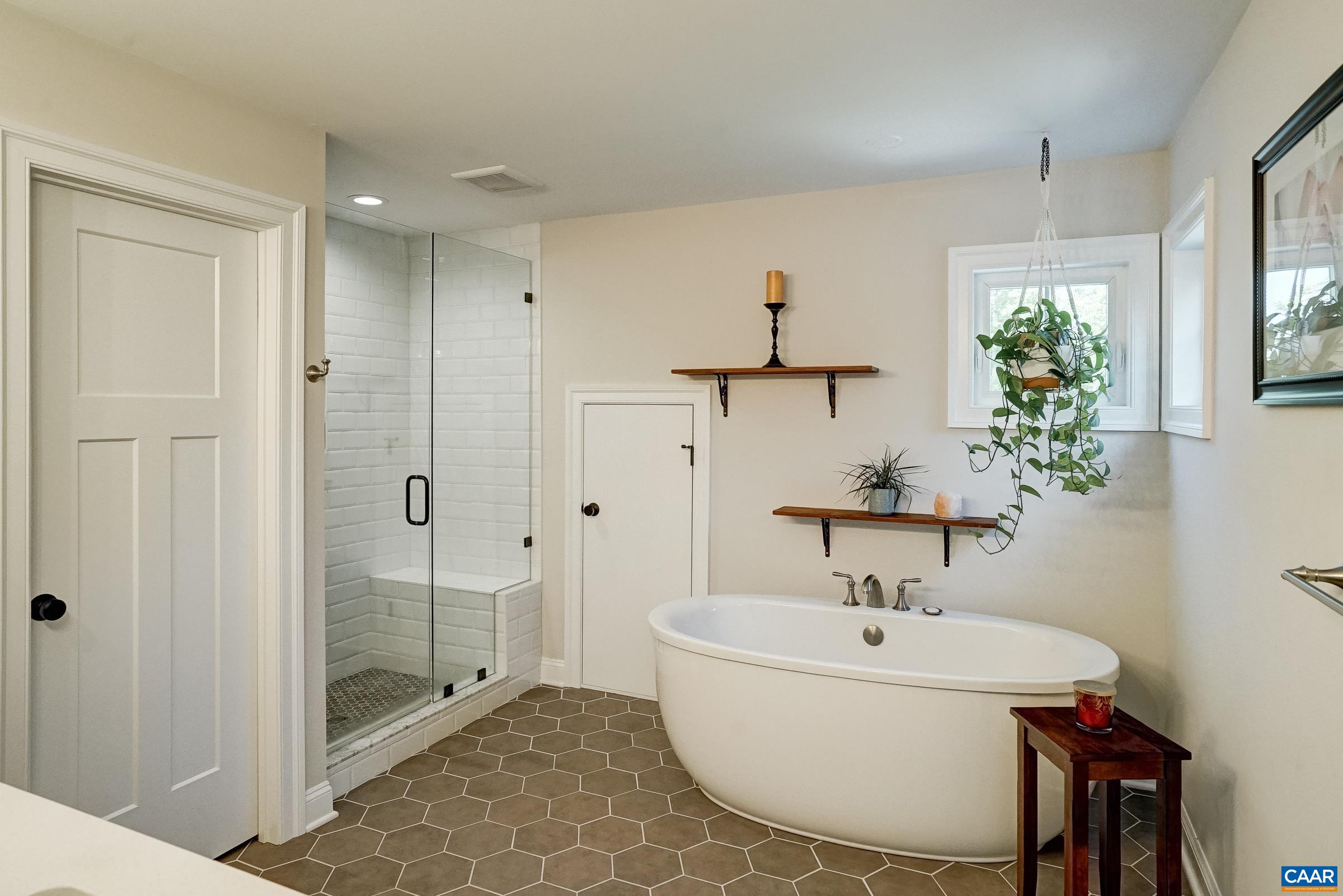 Primary bathroom with freestanding soaking tub and frameless glass shower.