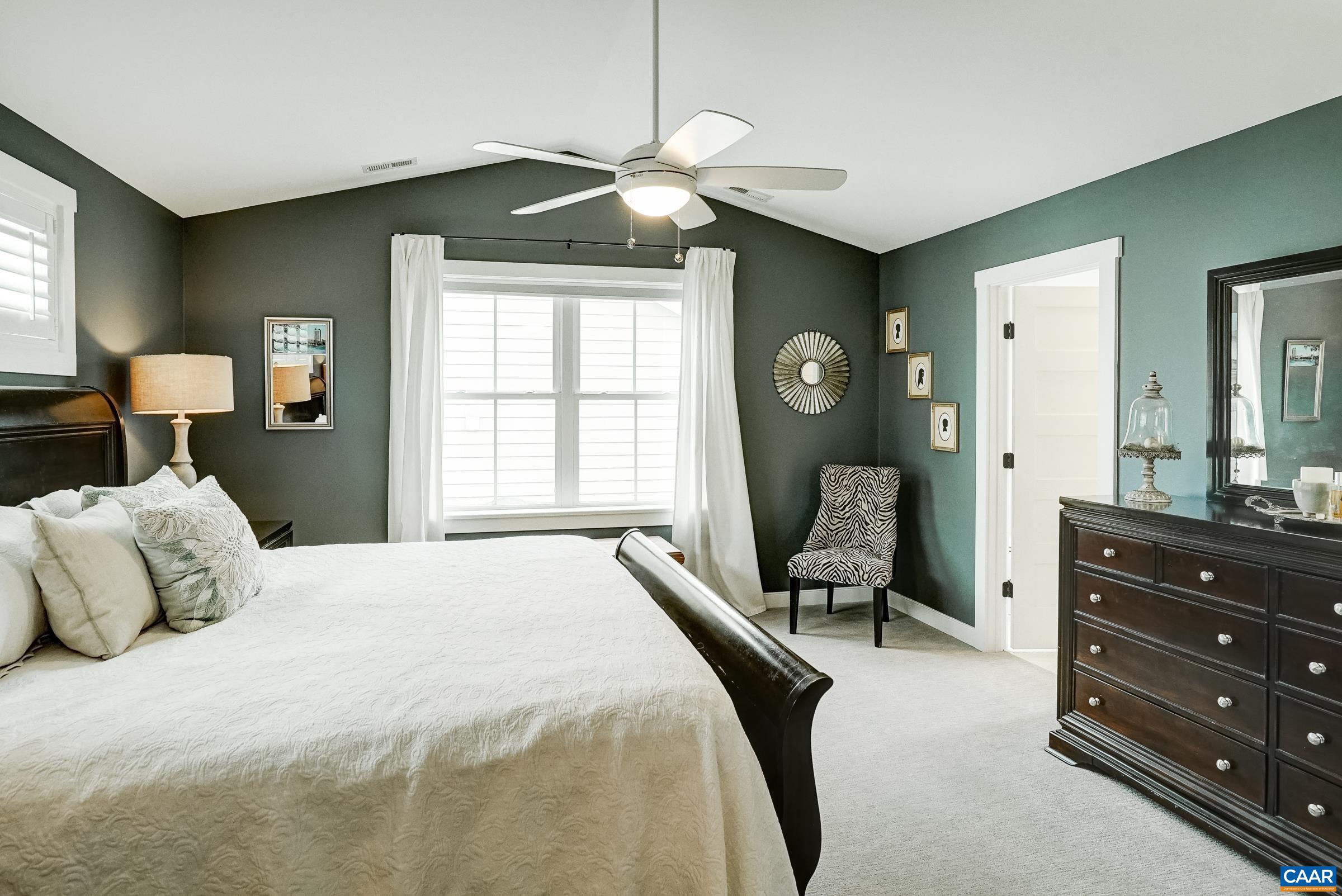 Vaulted primary suite on second floor features ceiling fan and ensuite bathroom. Vaulted primary suite on second floor features ceiling fan and ensuite bathroom.