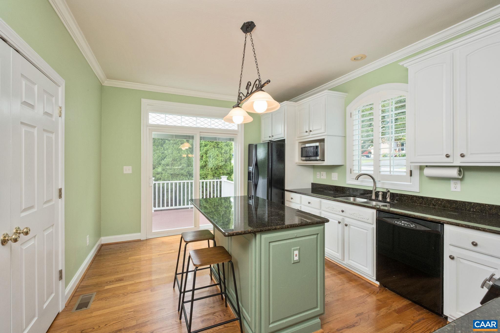 The kitchen features granite countertops, a large island, a breakfast bar space, crown molding, an arch over the window, and a transom window for additional light. The kitchen features granite countertops, a large island, a breakfast bar space, crown molding, an arch over the window, and a transom window for additional light.