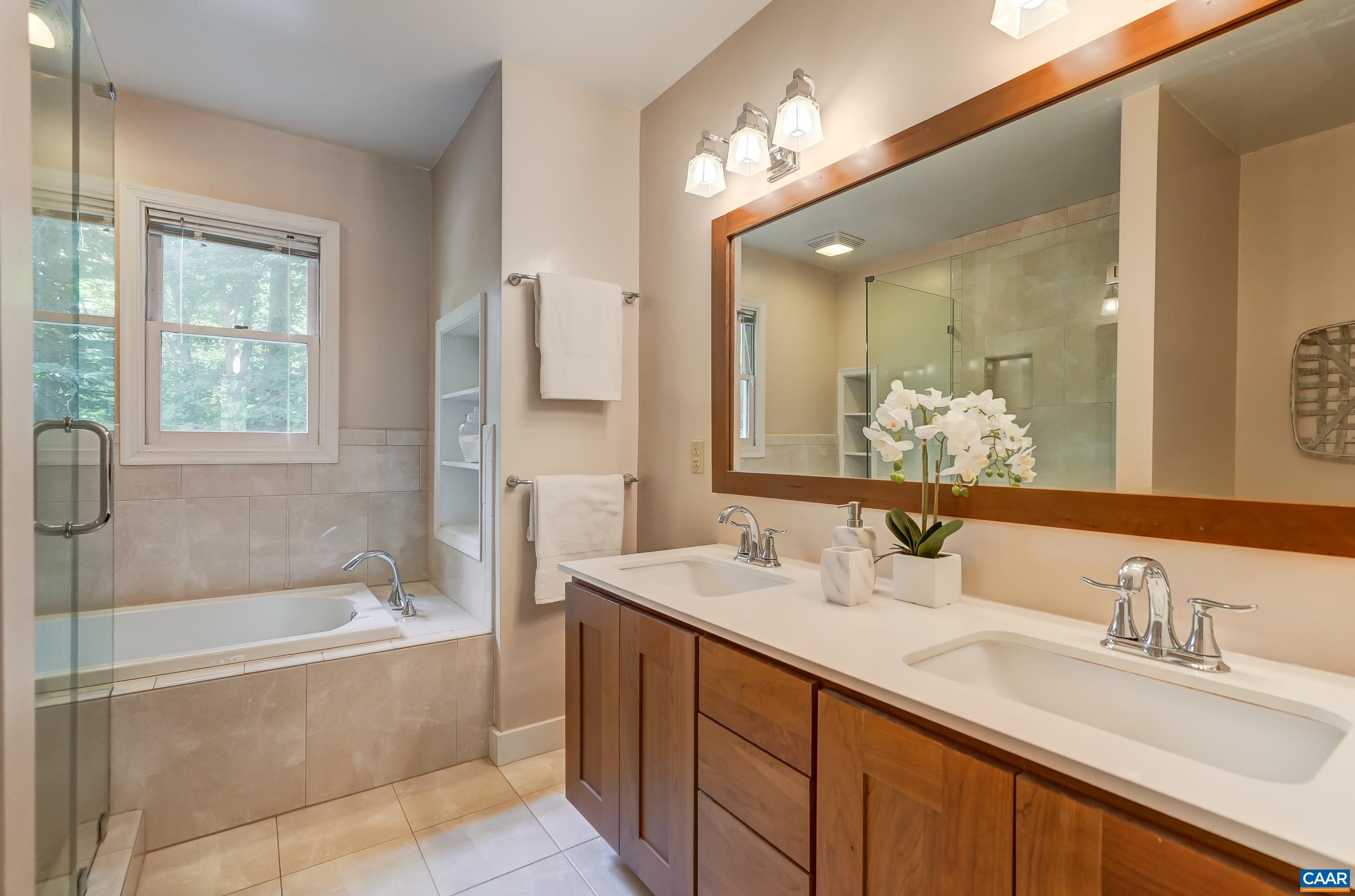 Remodeled primary bathroom with cherry cabinets, soaking tub and frameless glass shower. Remodeled primary bathroom with cherry cabinets, soaking tub and frameless glass shower.