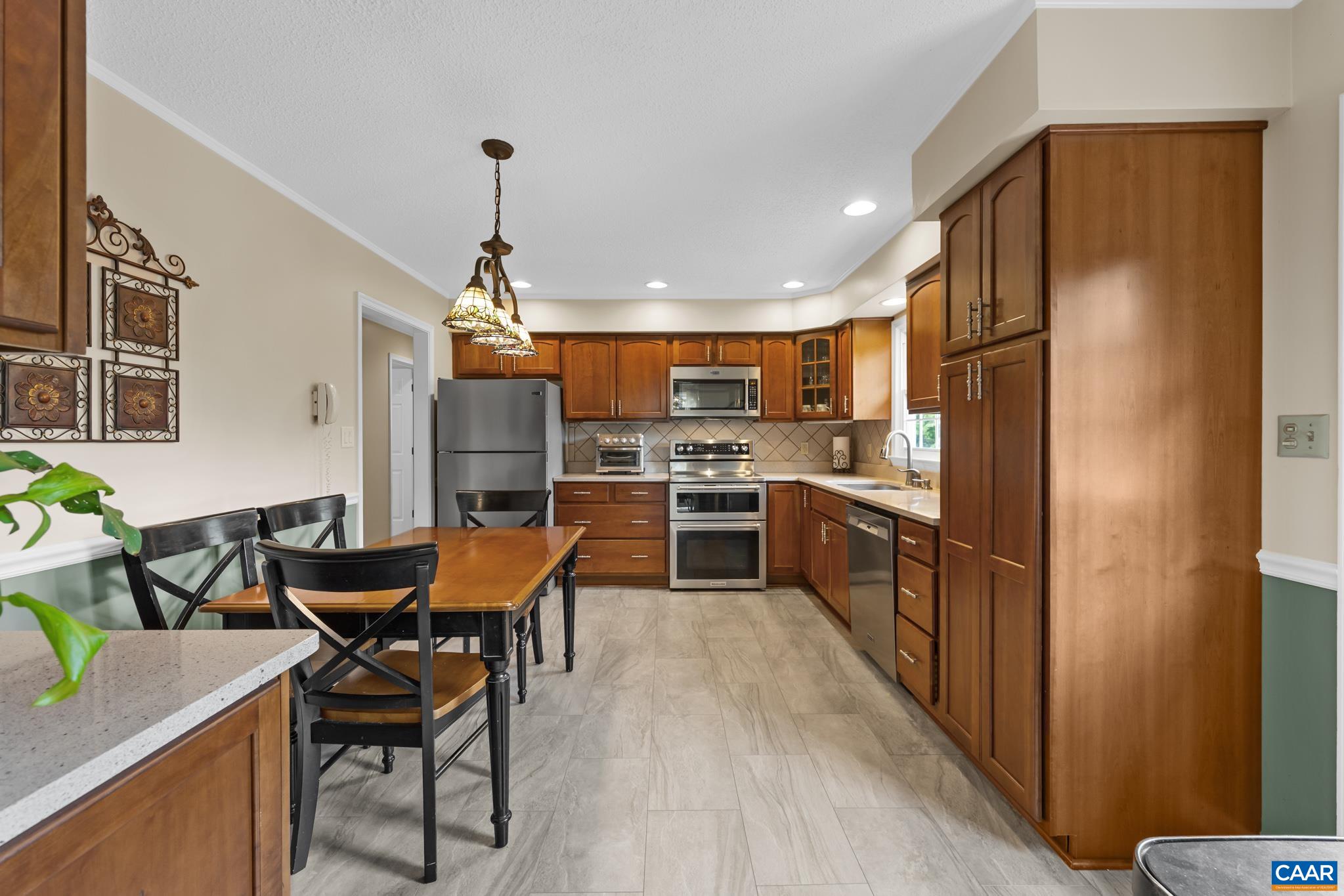 Step into this bright, open kitchen and dining space! Features rich wood cabinetry, stainless steel appliances, stylish flooring, and an inviting eating area under charming pendant lighting. Designed for easy cooking and effortless entertaining!