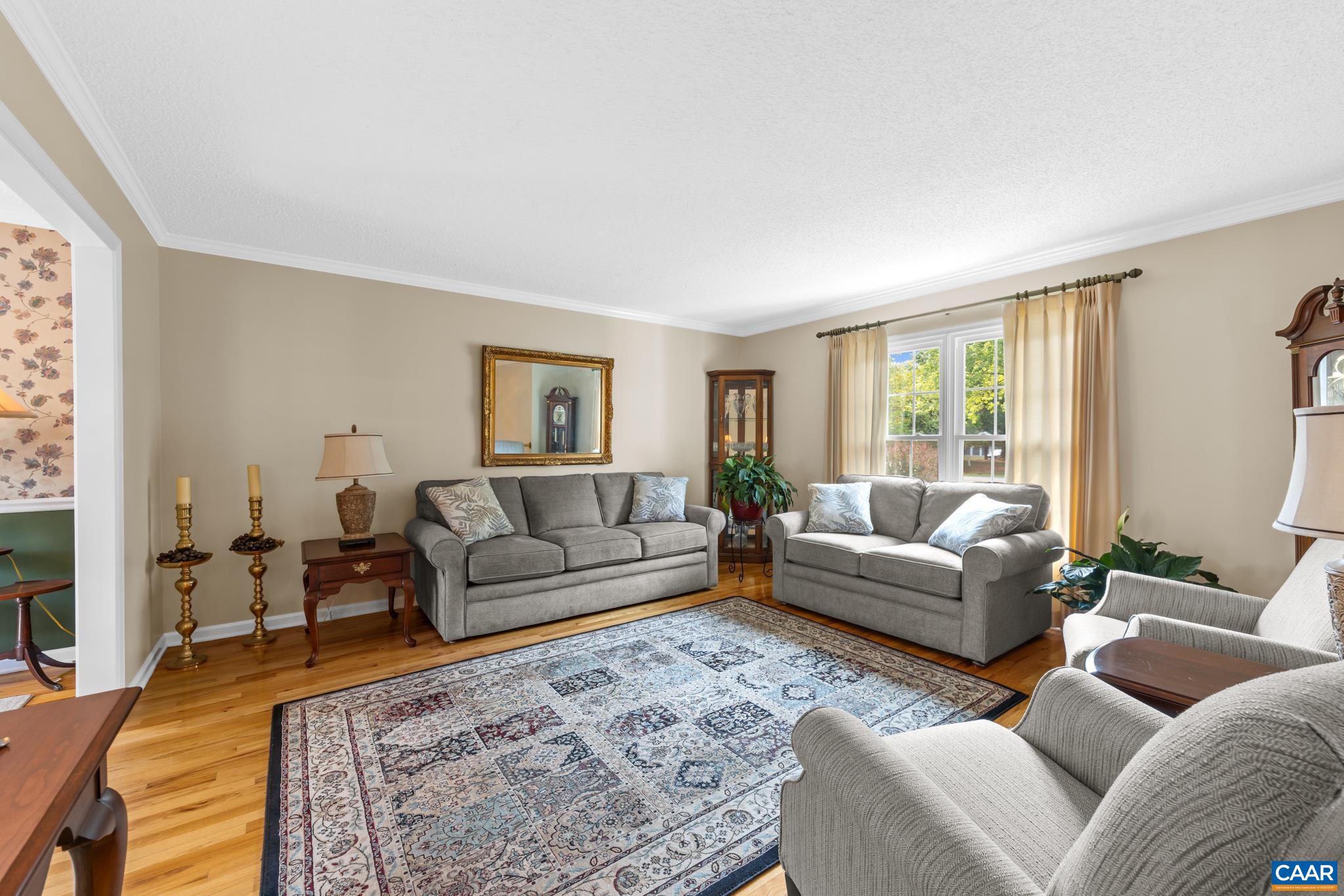 Relax in style in this bright, open living room! Highlights include gleaming hardwood floors, a wide sunlit window, classic crown molding, and seamless flow into adjoining spaces. Warm, elegant, and perfectly designed for everyday comfort!