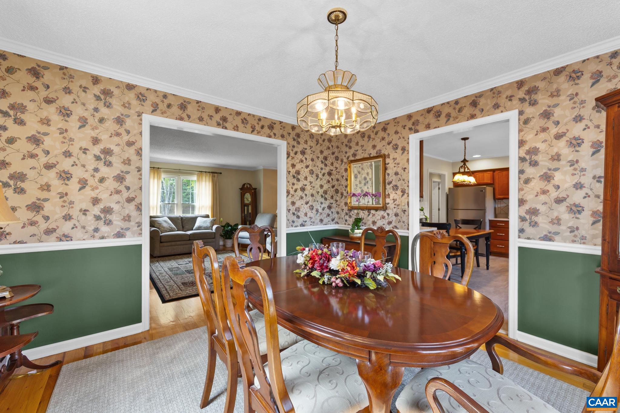 Elegance meets comfort in this formal dining room! Highlights include gleaming hardwood floors, classic chair rail molding, rich wood furnishings, and a sparkling chandelier. Seamless flow to adjacent living areas makes hosting a breeze!