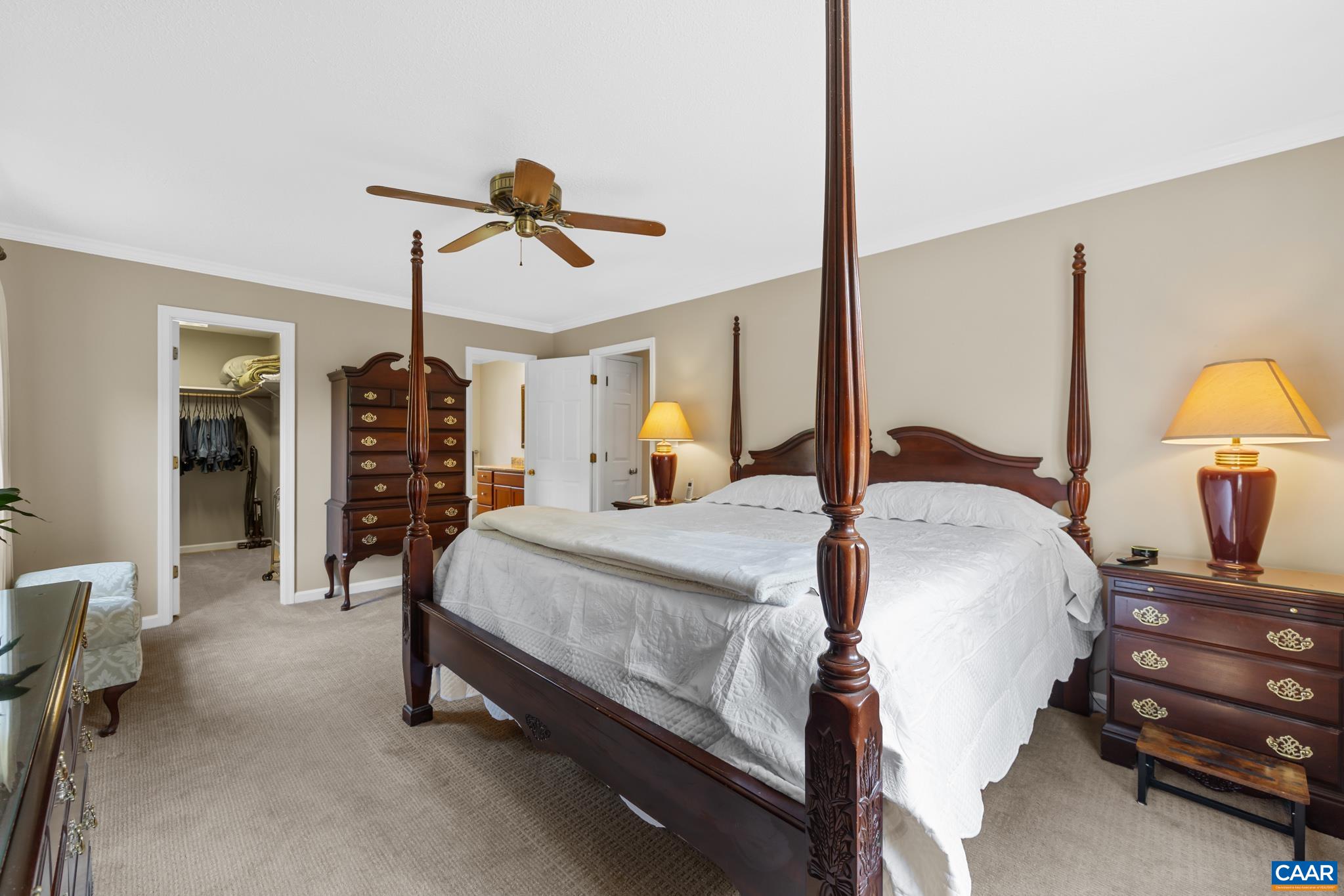 Relax in total comfort in this spacious primary bedroom! Features soft carpeting, crown molding, a wood ceiling fan, and direct access to an ensuite bath and walk-in closet. A true sanctuary!