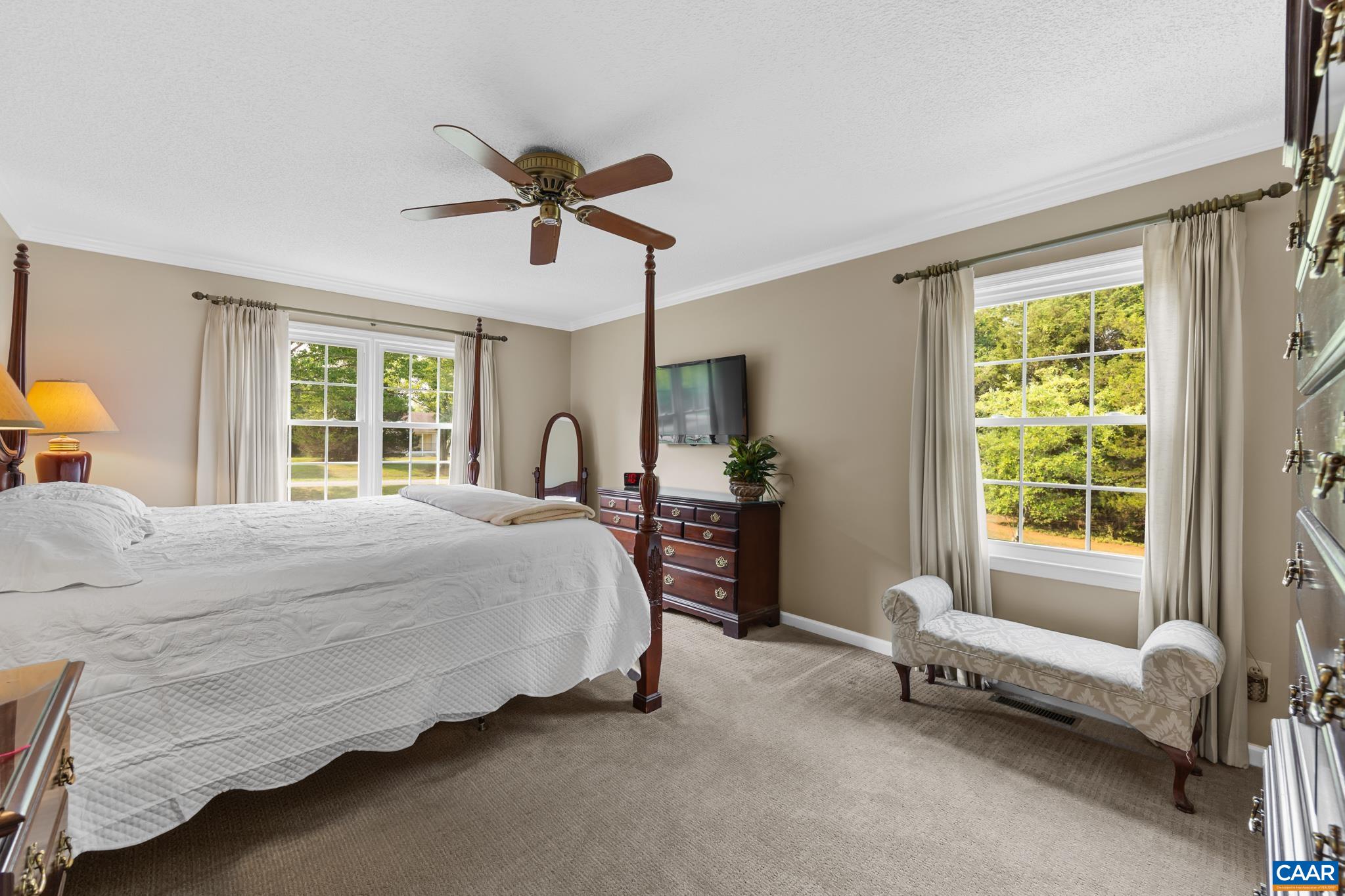 Retreat to this spacious primary bedroom suite! Highlights include crown molding, soft carpeting, an elegant four-poster bed, and bright windows with a charming window bench. A peaceful, sunlit oasis designed for ultimate relaxation and comfort!