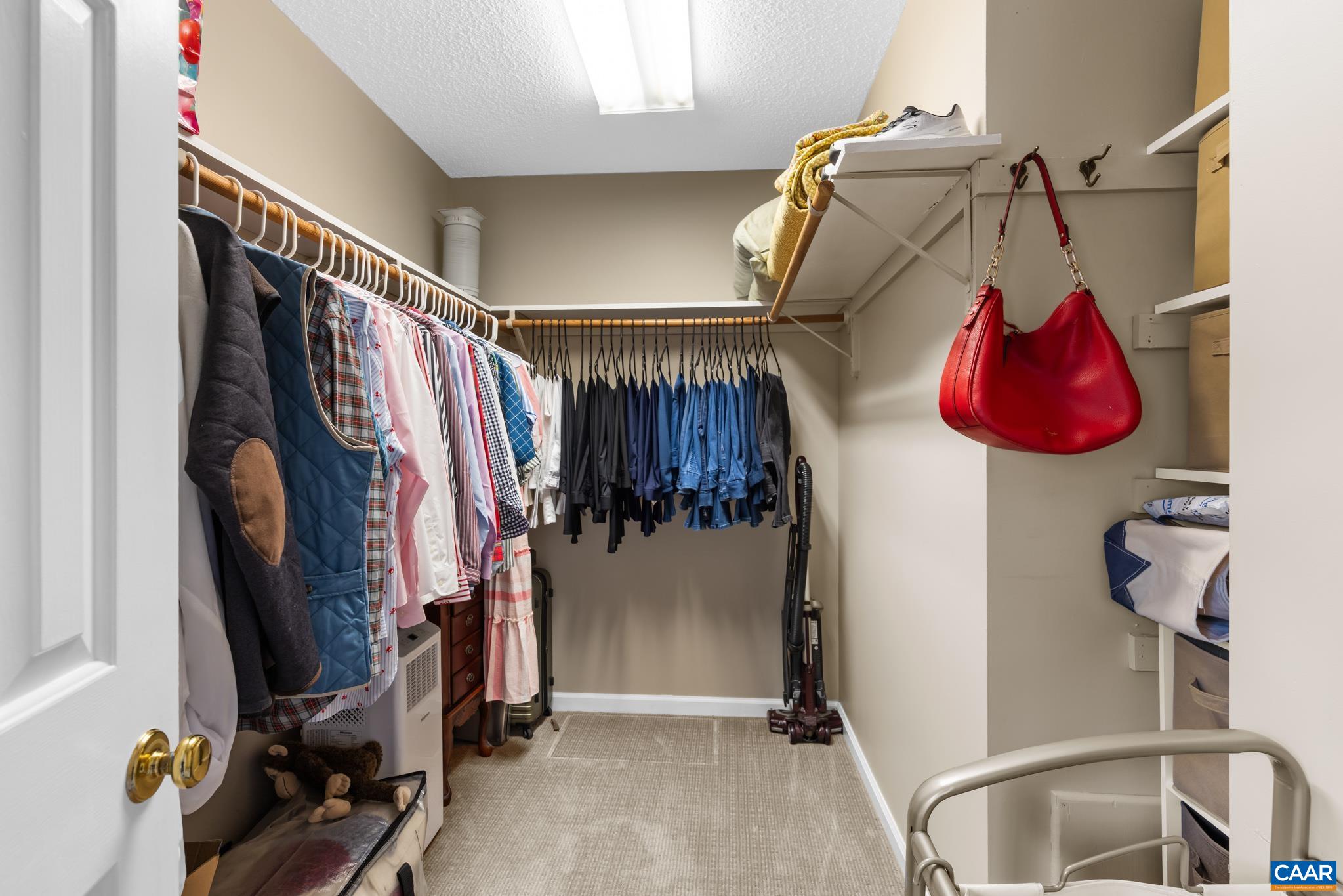Enjoy exceptional organization in this spacious walk-in closet! Featuring built-in wire hanging racks, upper shelf storage, and soft carpet underfoot. Plenty of room for clothing, shoes, and accessories to keep your wardrobe tidy and accessible!